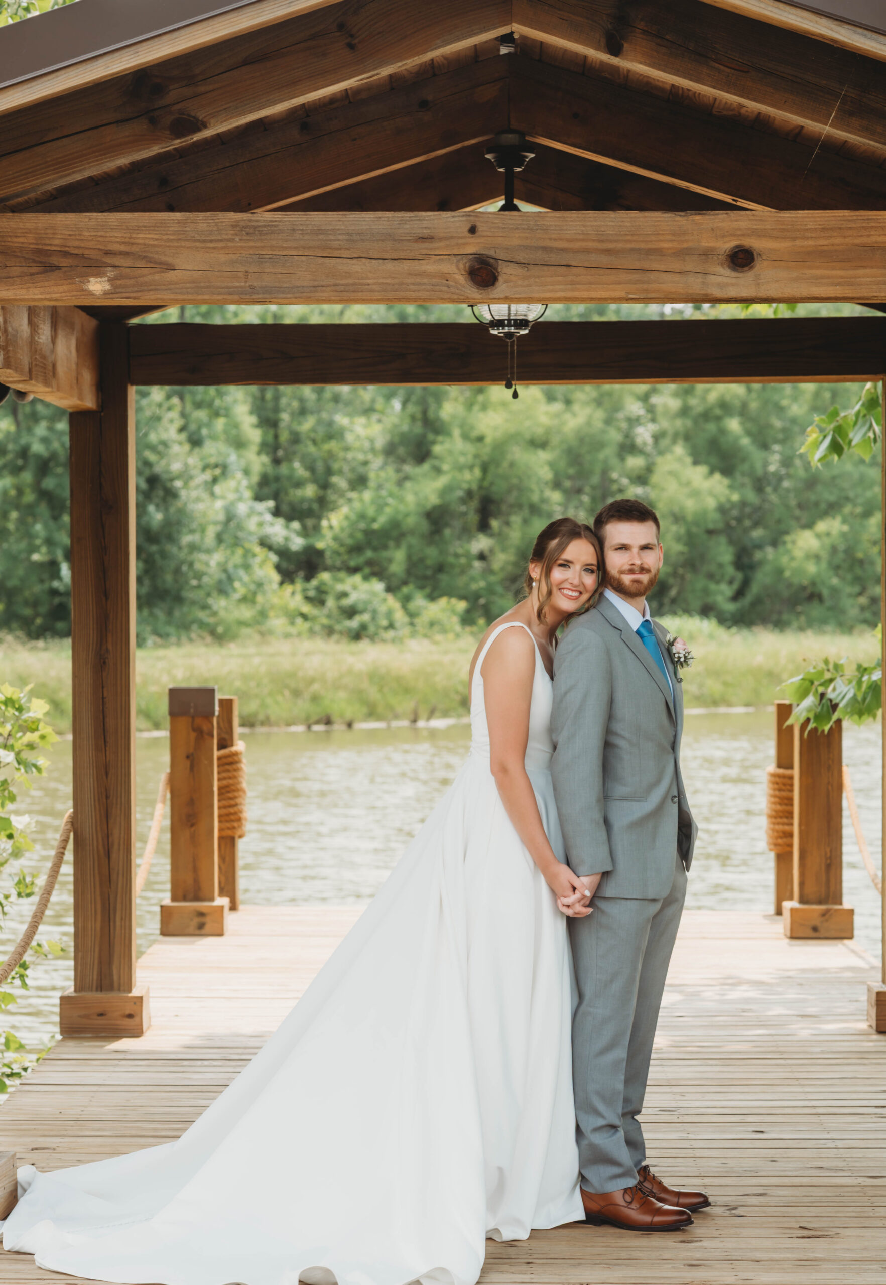 Anna & Jaden pose under the Pond pavilion, her train spread on the dock boards, at Covey Creek.