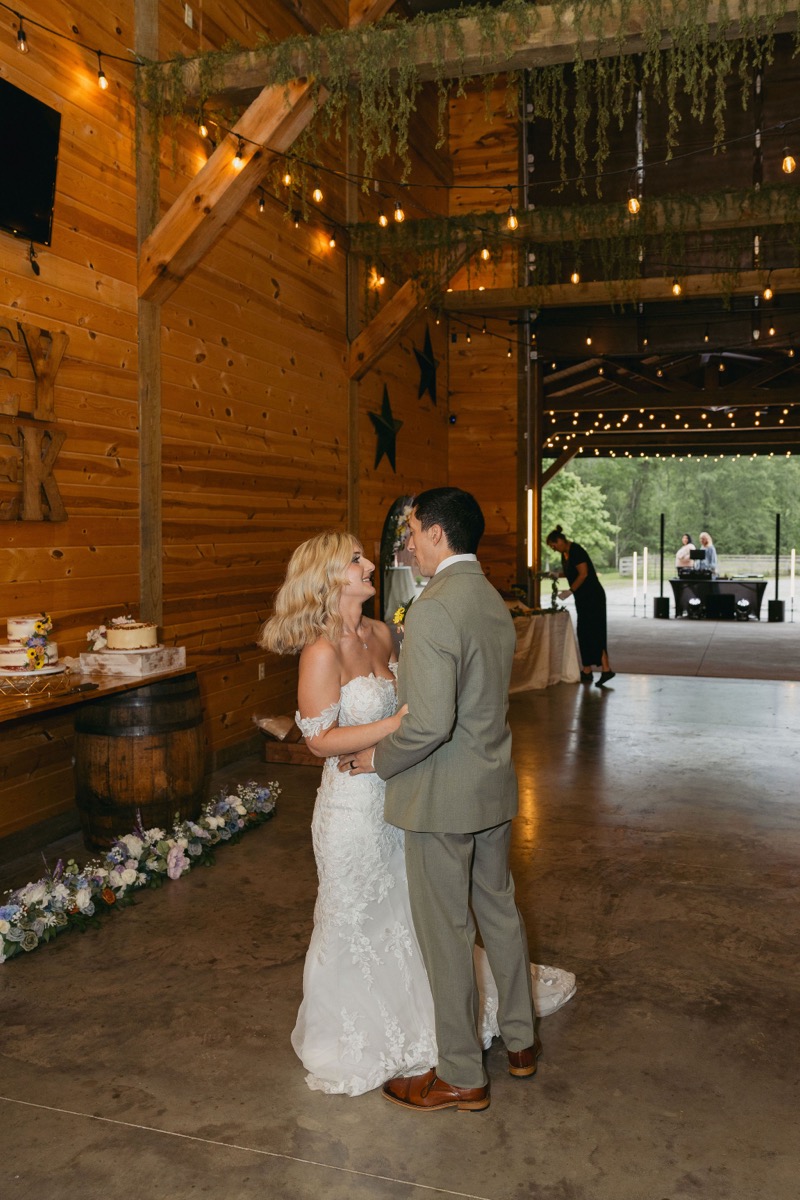 Brianna & Michael dance in the barn under Edison lights beside floral cakes and star decor at Covey Creek.