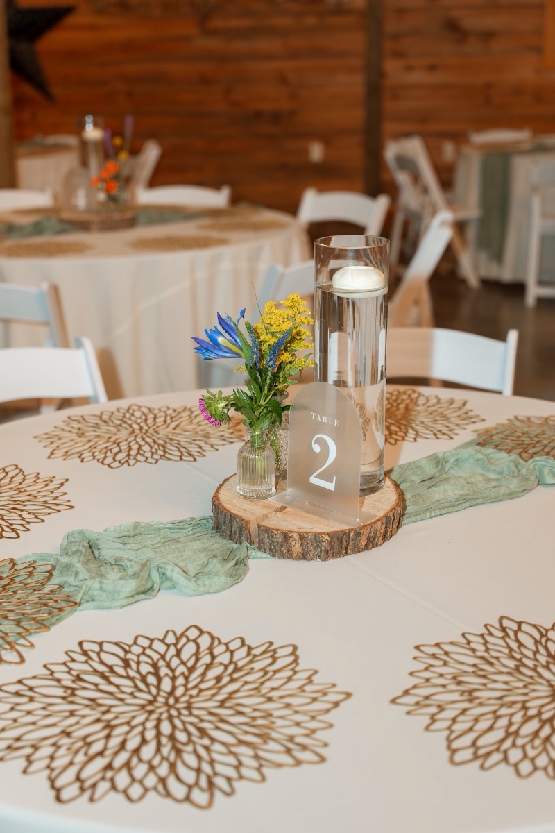 Caitlin & Daniel Table 2 centerpiece with floating candle, wildflowers, and sage runner indoors at Covey Creek