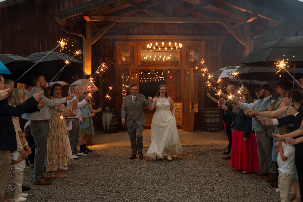 Caitlin & Daniel exit the barn hand-in-hand through a sparkler tunnel on a rainy night at Covey Creek