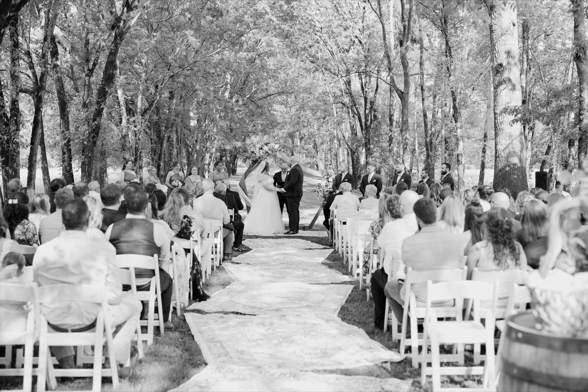 Guests face Carly & Lucas under a floral wooden arbor along the Tunnel of Love aisle at Covey Creek