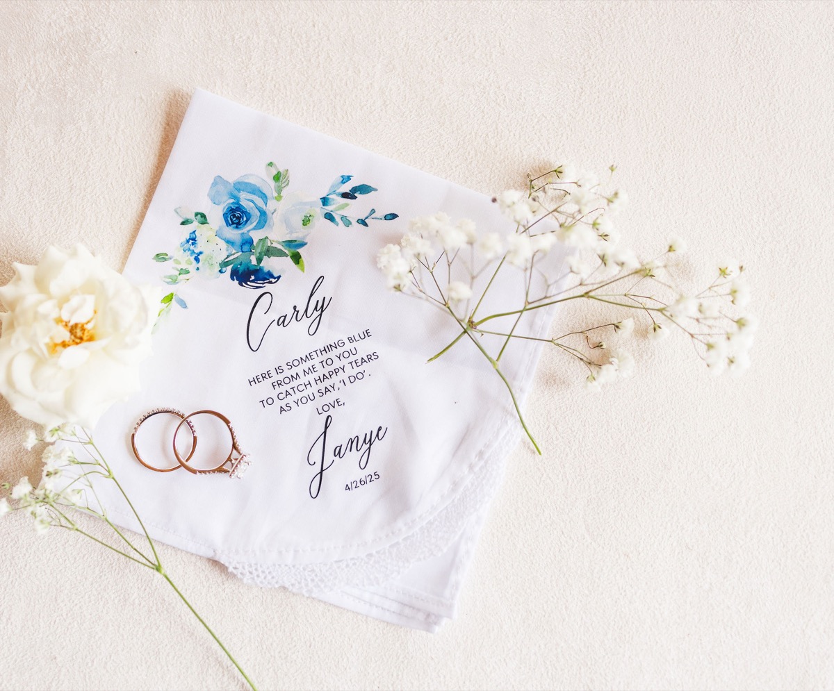 Carly & Lucas rose-gold rings rest on a lace something-blue handkerchief with white rose at Covey Creek