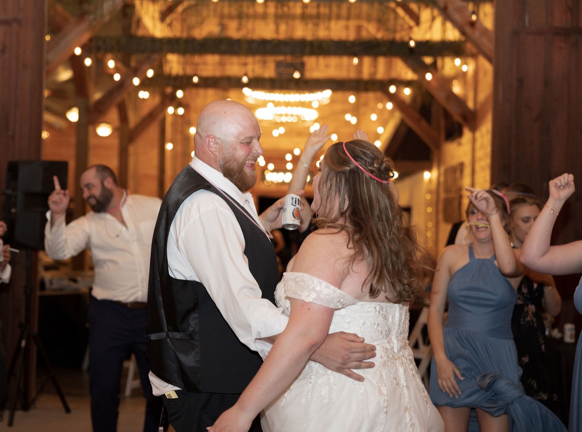Carly & Lucas dance among guests under warm string lights at their Covey Creek indoor reception
