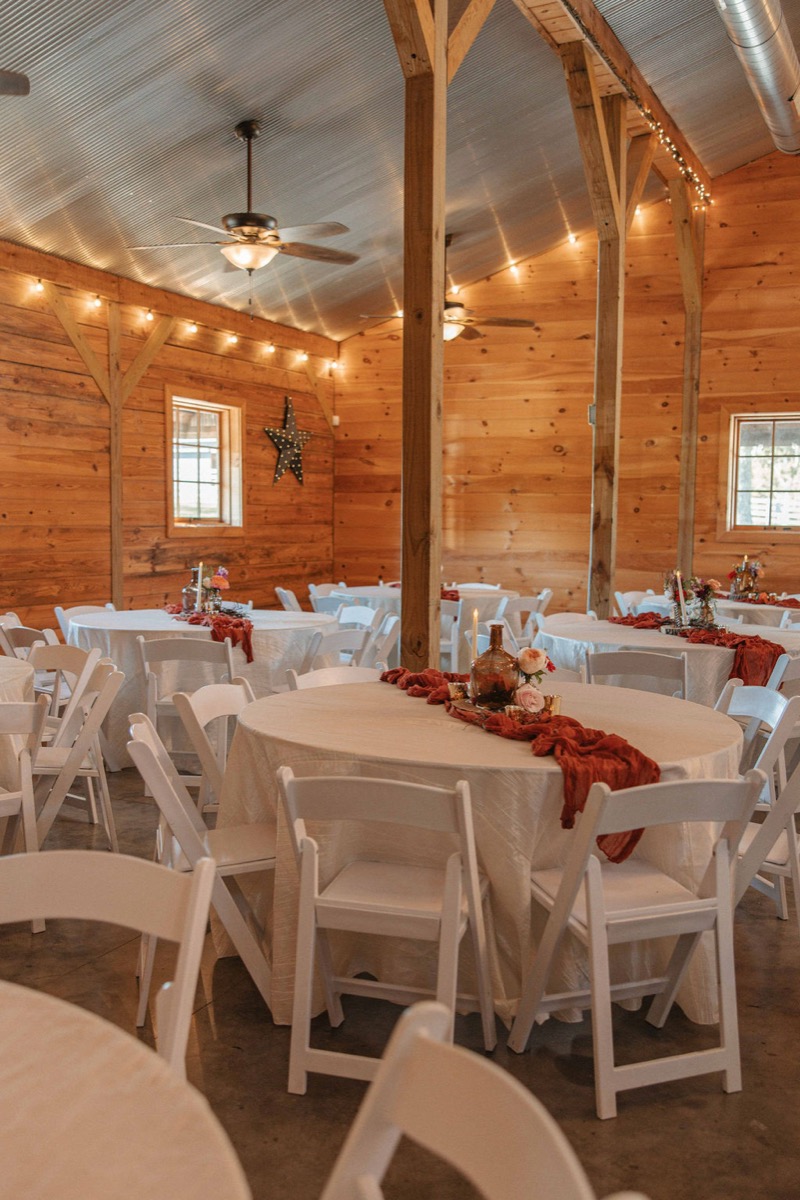 Claire & Jacob reception tables with terracotta runners and amber glass in the barn at Covey Creek