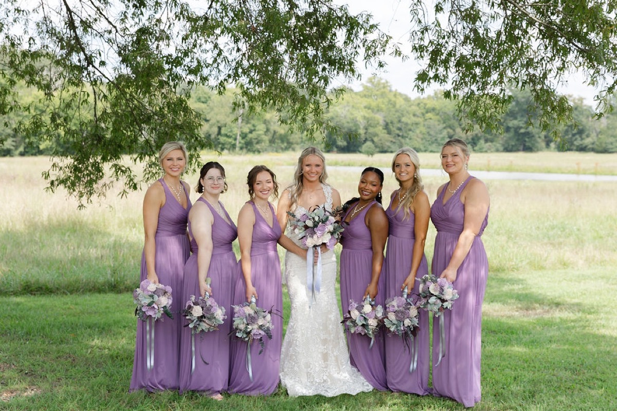 Courtney & Brett bridal party in lavender dresses pose under a tree by the pond meadow at Covey Creek