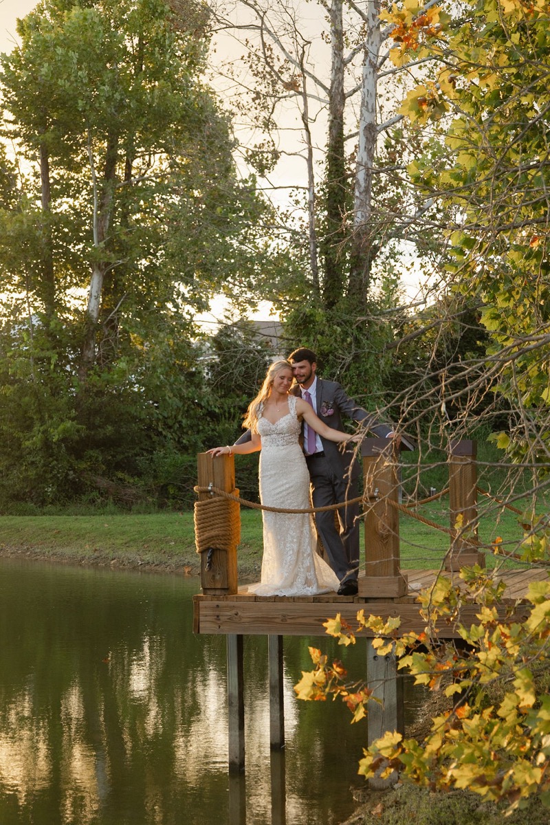 Courtney & Brett stand close on the wooden Pond dock with rope railings at golden hour at Covey Creek