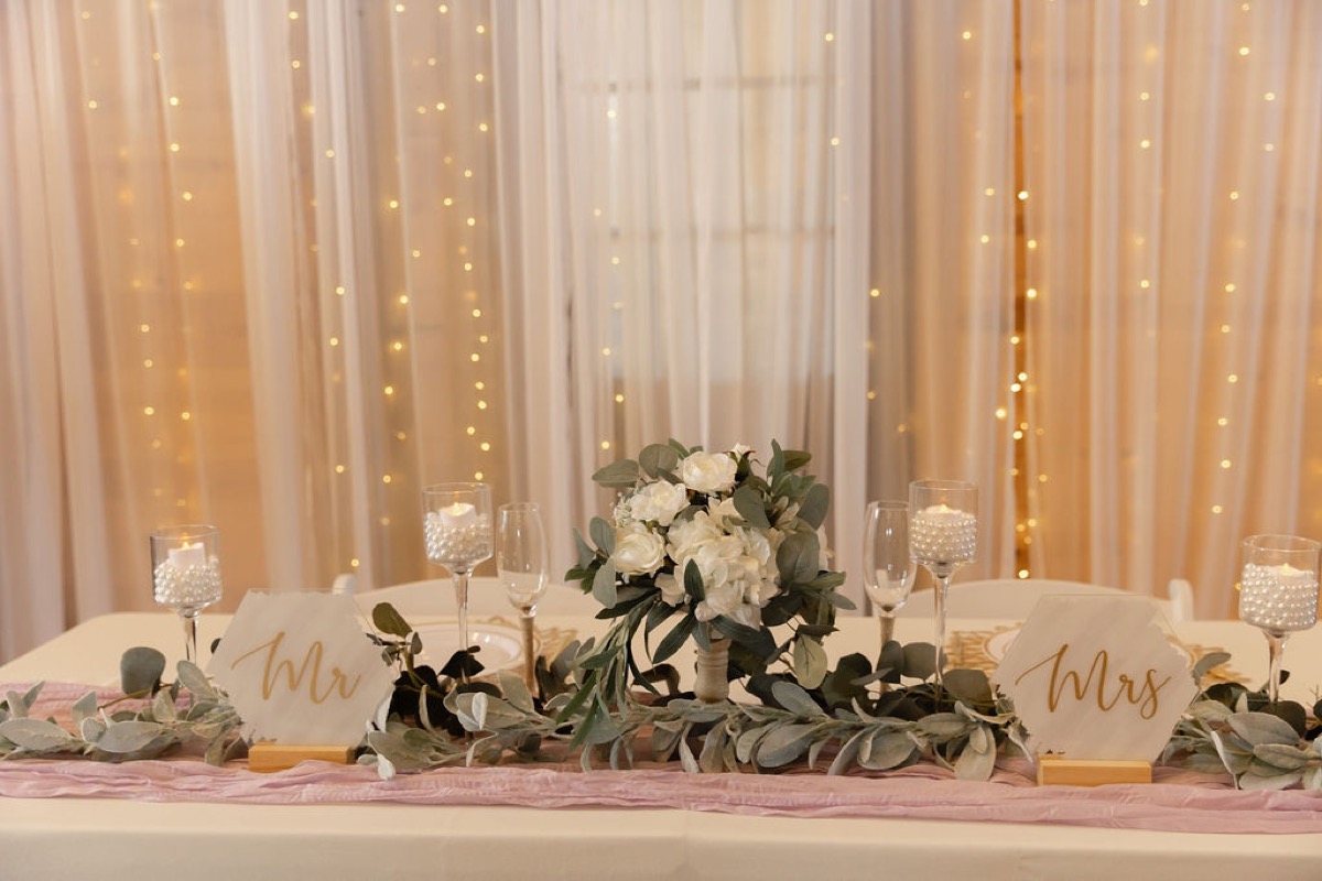 Courtney & Brett sweetheart table with Mr & Mrs signs, greenery, and candlelight at Covey Creek reception