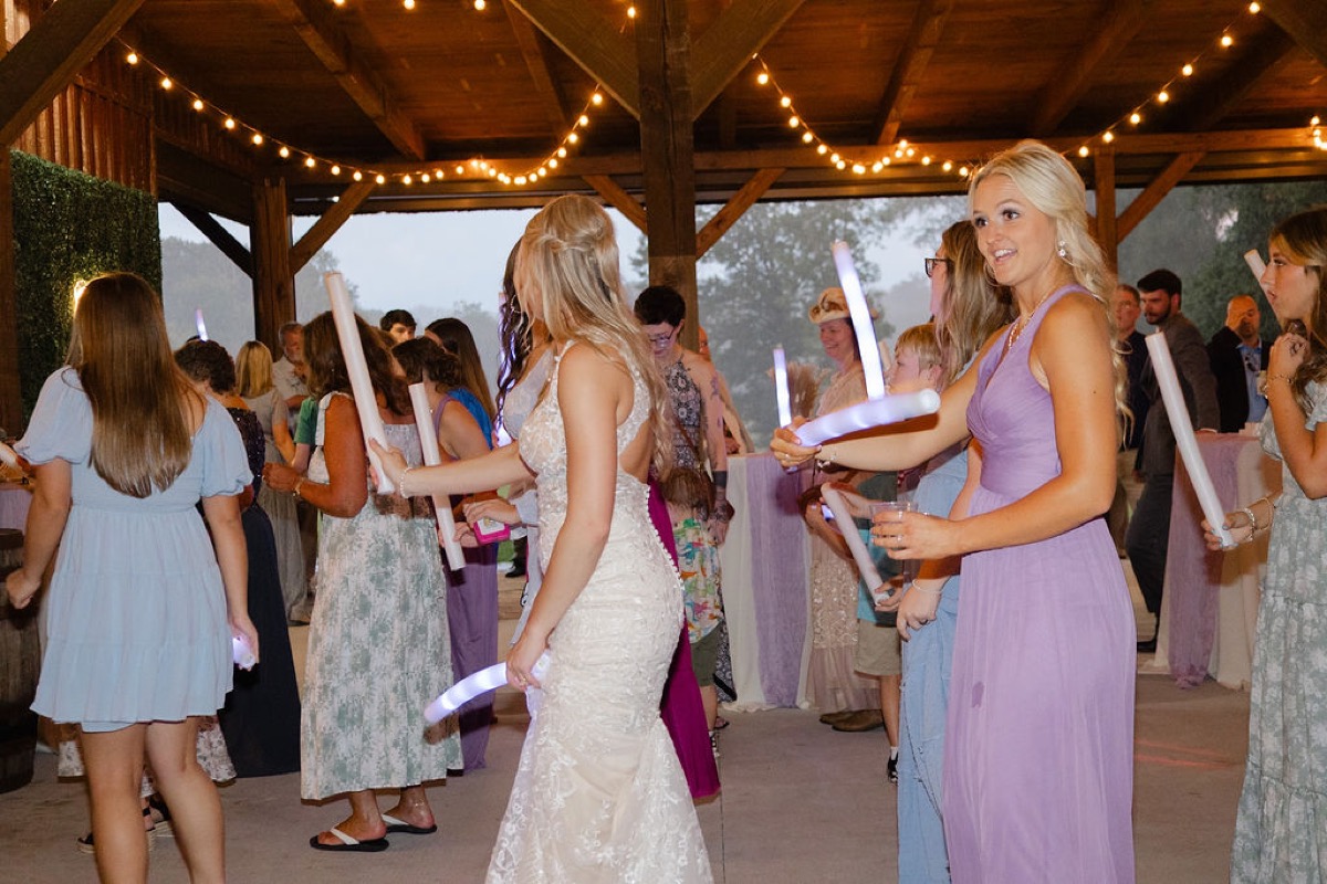Courtney & Brett reception glow-stick celebration under timber beams and string lights at Covey Creek