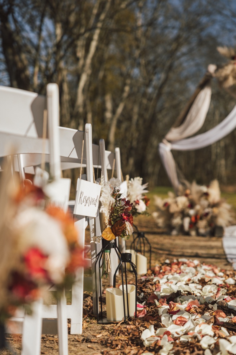 Reserved chairs, candle lanterns, and rose petals line Danika & Troy's ceremony aisle at Covey Creek