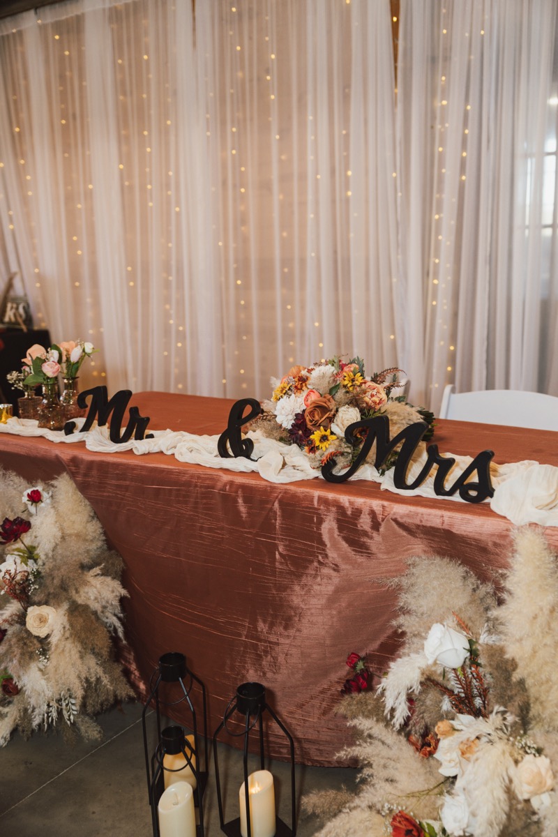 Mr. & Mrs. sweetheart table with rust satin and floor pampas for Danika & Troy at Covey Creek