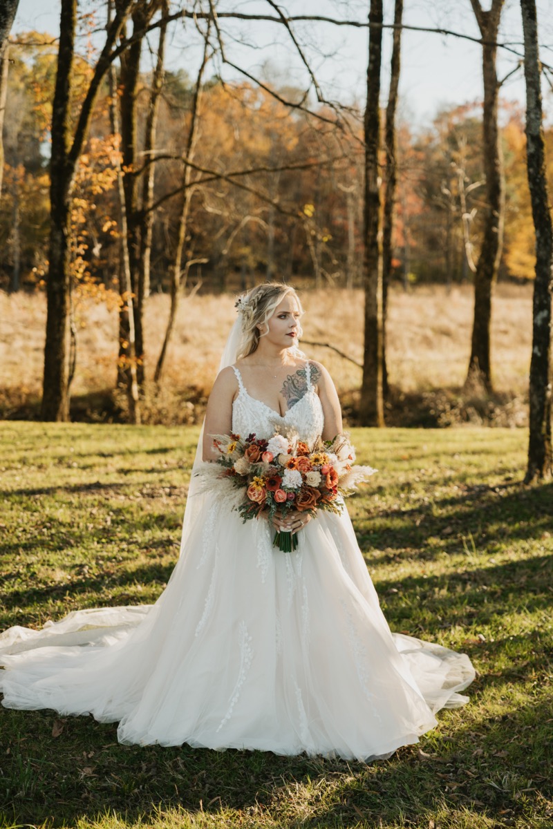 Danika holds her autumn orange bouquet in a lace gown for Danika & Troy's portraits at Covey Creek