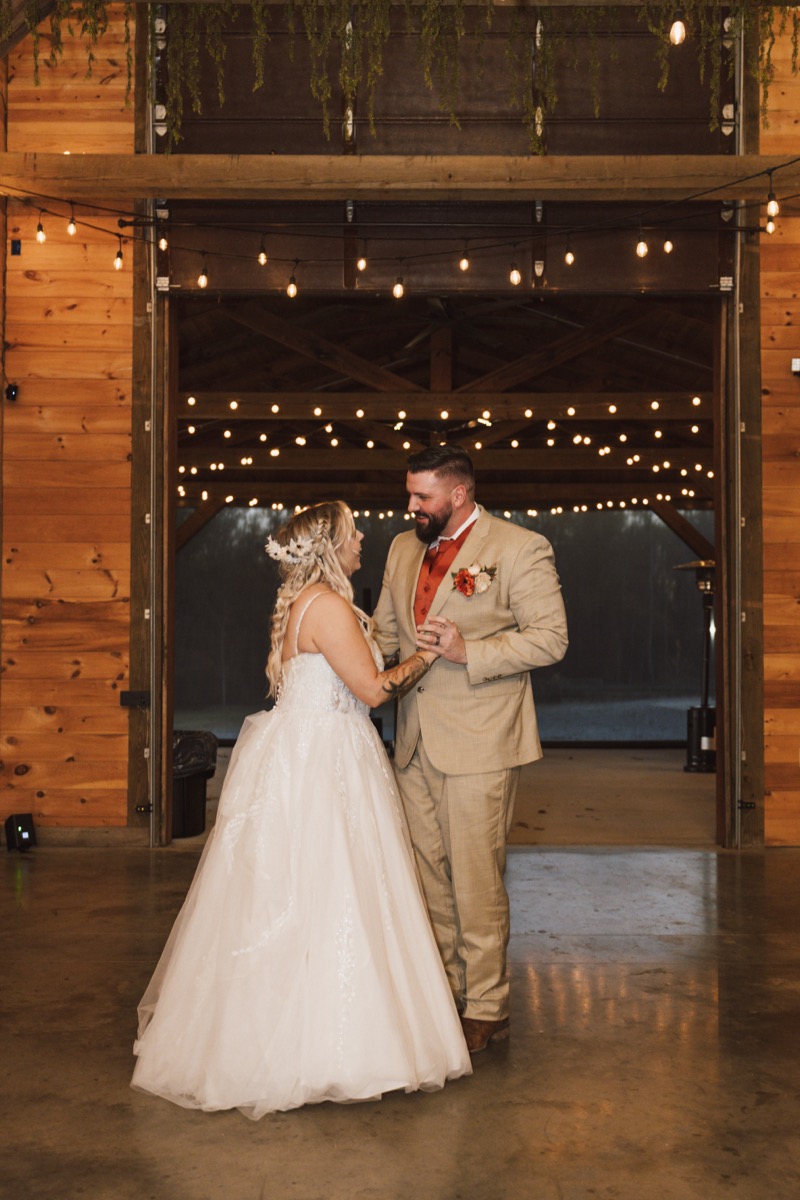 Danika & Troy share a first dance under warm Edison string lights in the barn at Covey Creek