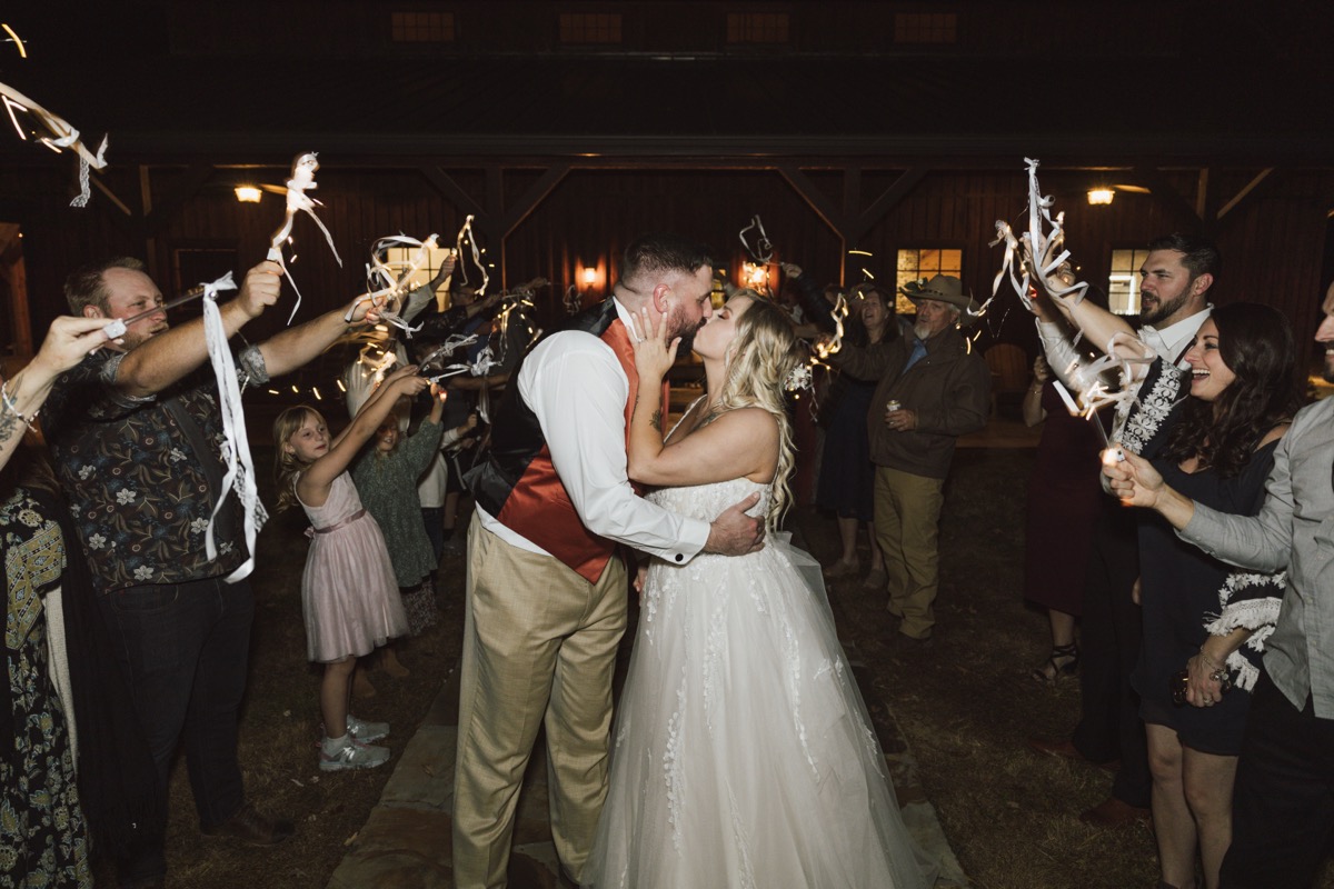 Danika & Troy kiss amid ribbon-wand streamers during their barn night send-off at Covey Creek