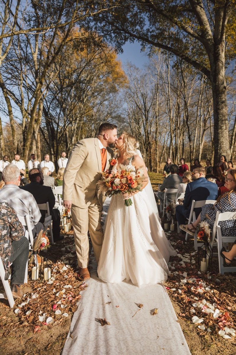 Danika & Troy kiss on the petal-strewn aisle as guests cheer after saying vows at Covey Creek