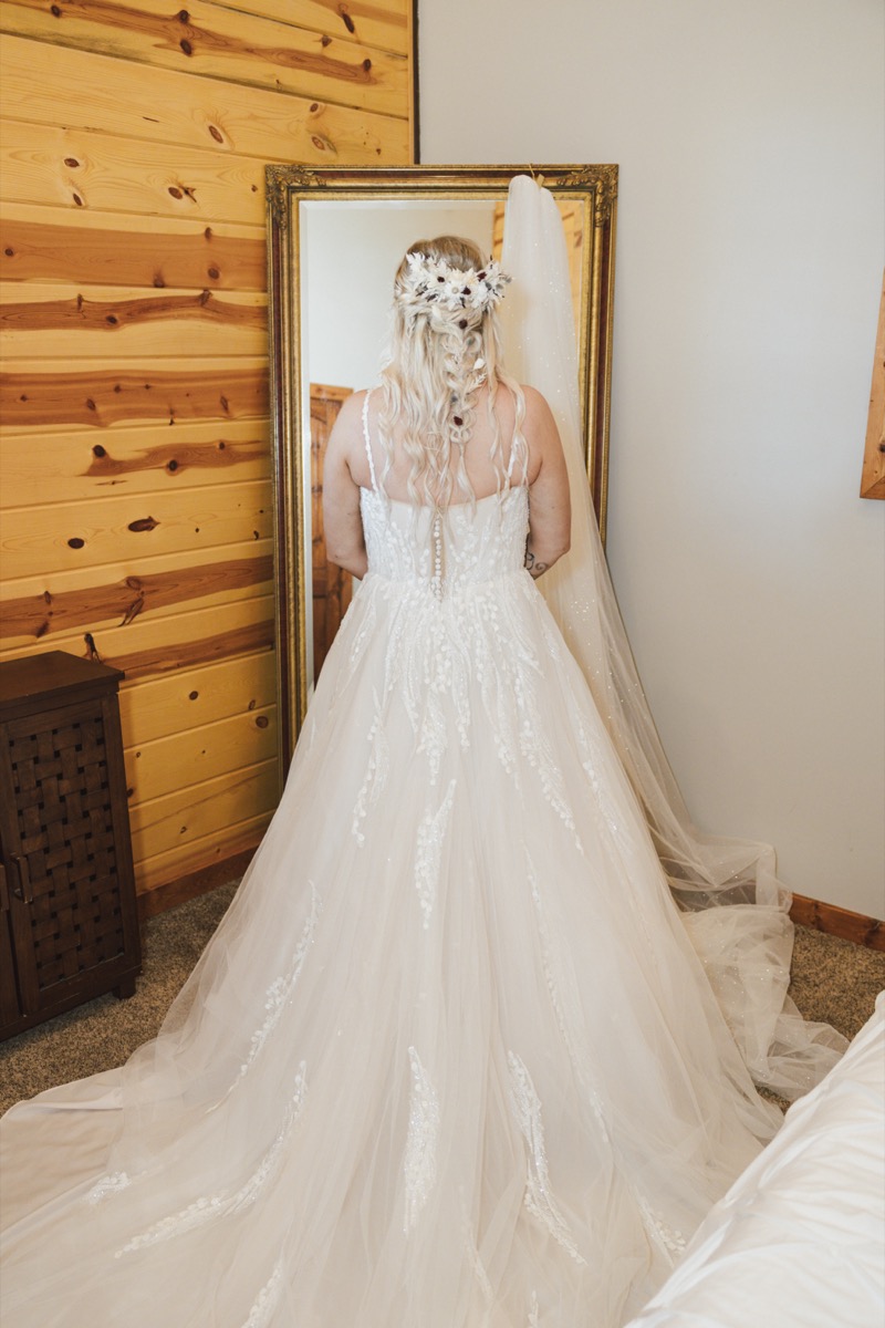 Danika shows her lace gown and floral crown before a gold mirror for Danika & Troy at Covey Creek