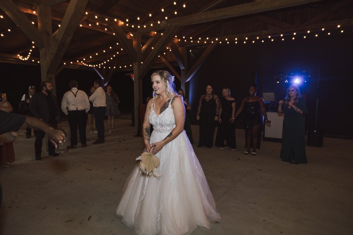 Danika holds her palm-leaf bouquet for the toss at Danika & Troy's reception at Covey Creek