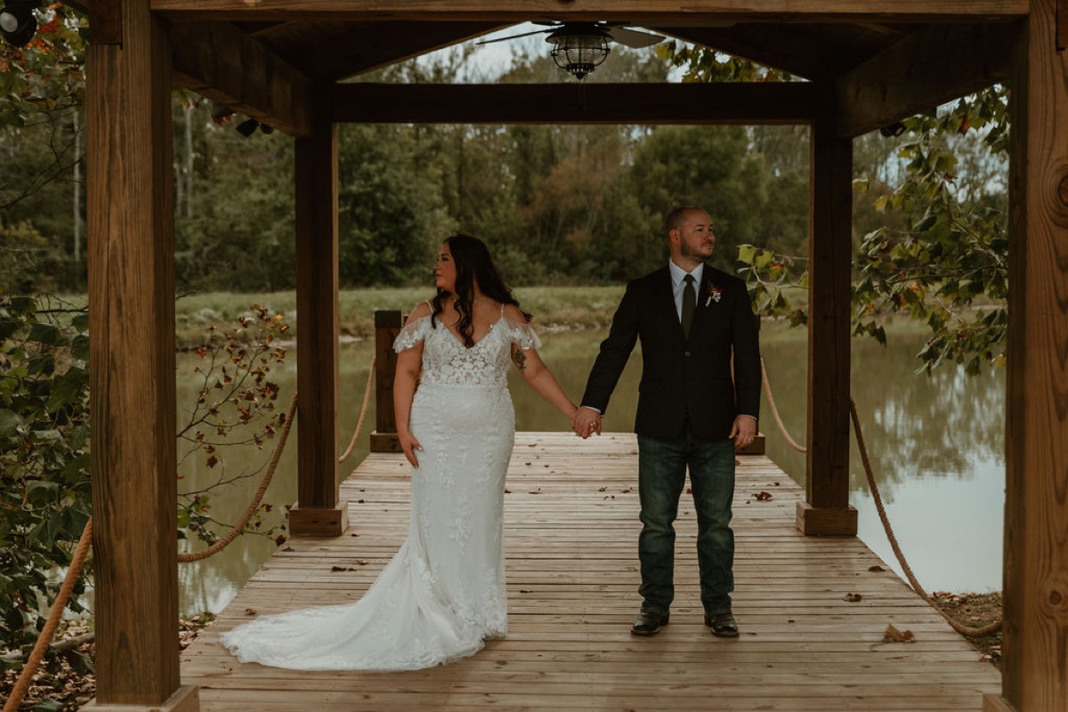 Elizabeth & Ashton hold hands on Covey Creek’s Pond pavilion dock, looking opposite ways over the water