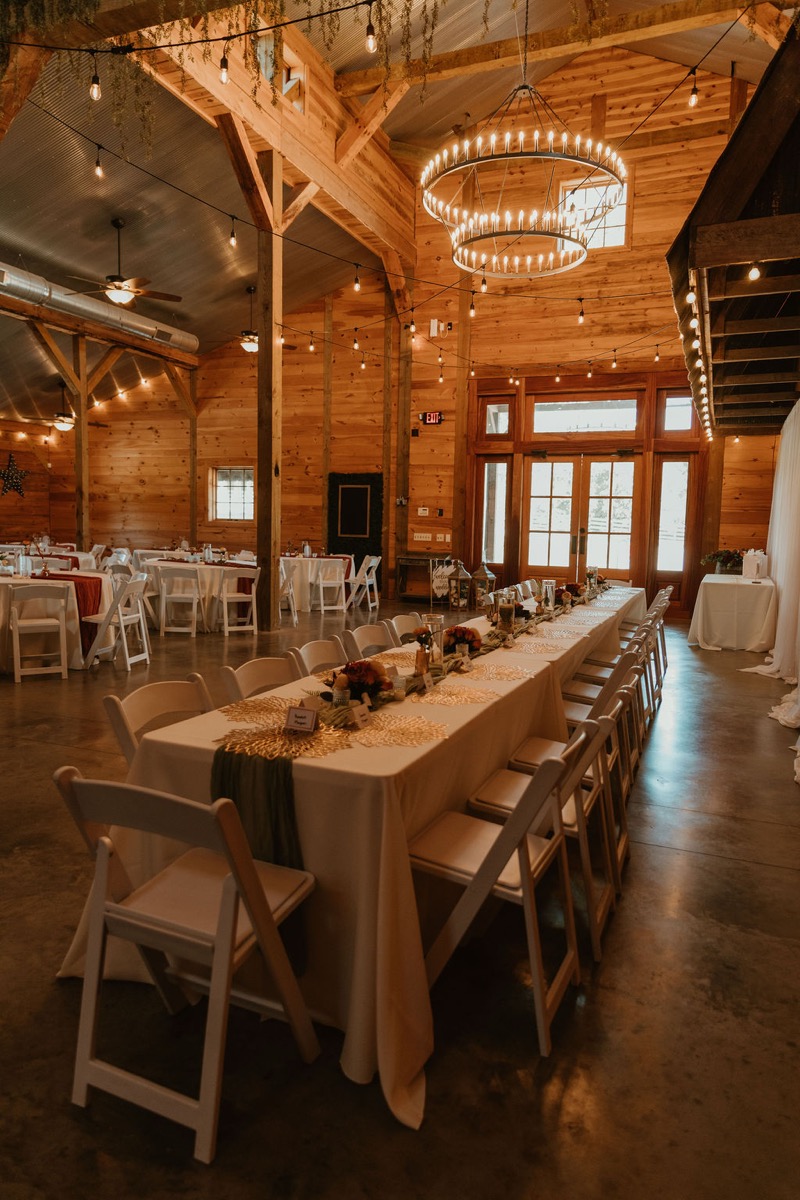 Covey Creek reception hall set for Elizabeth & Ashton with long head table, round guest tables, and string lights