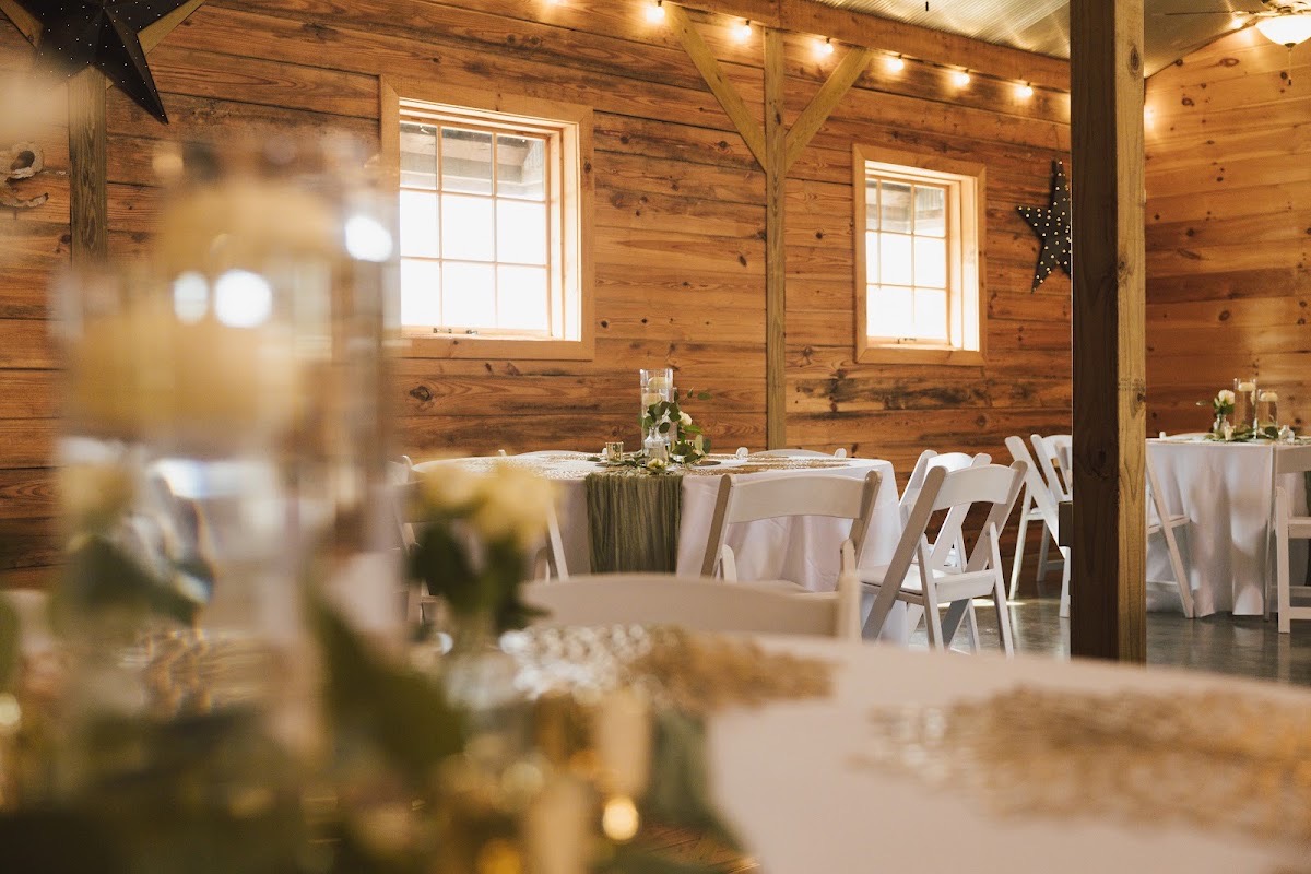 Round tables with floating candles and sage runners fill Emily & Bryan's wood-paneled indoor reception at Covey Creek.