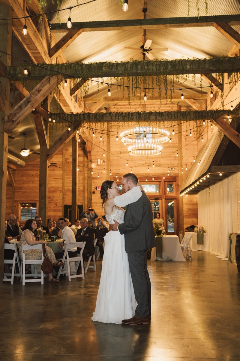 Emily & Bryan share their first dance under draped greenery and string lights in the indoor reception at Covey Creek.