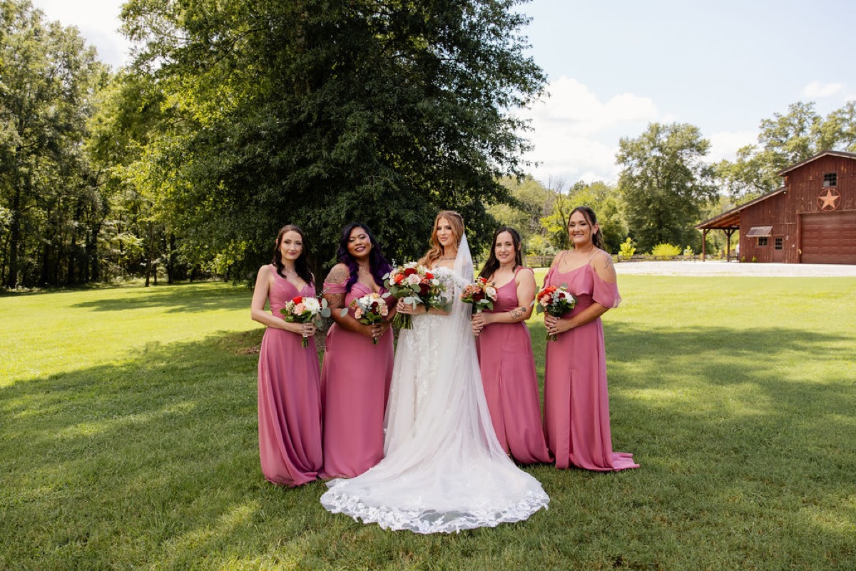 Erica & Randall bridal party on the lawn—bride with lace train, dusty-rose bridesmaids, red barn at Covey Creek