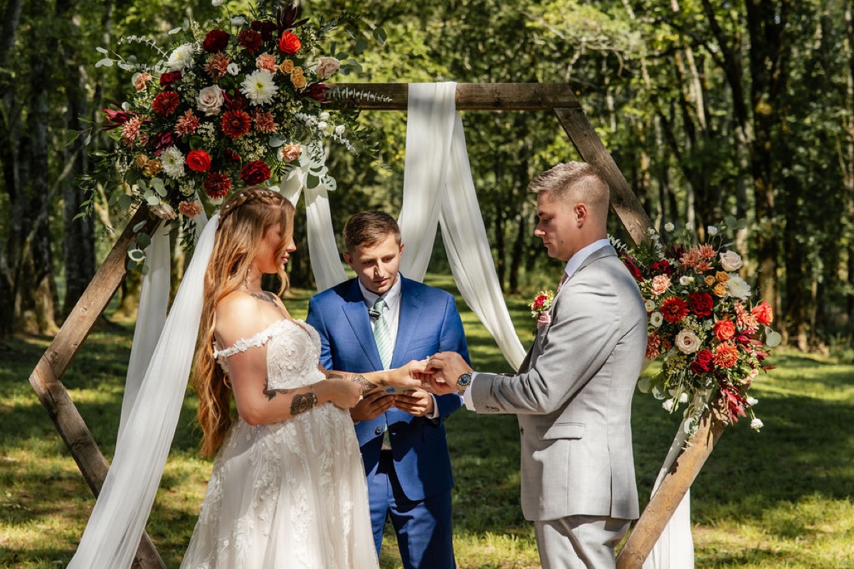 Erica & Randall exchange rings under the floral hexagonal arbor at Covey Creek’s Tunnel of Love ceremony