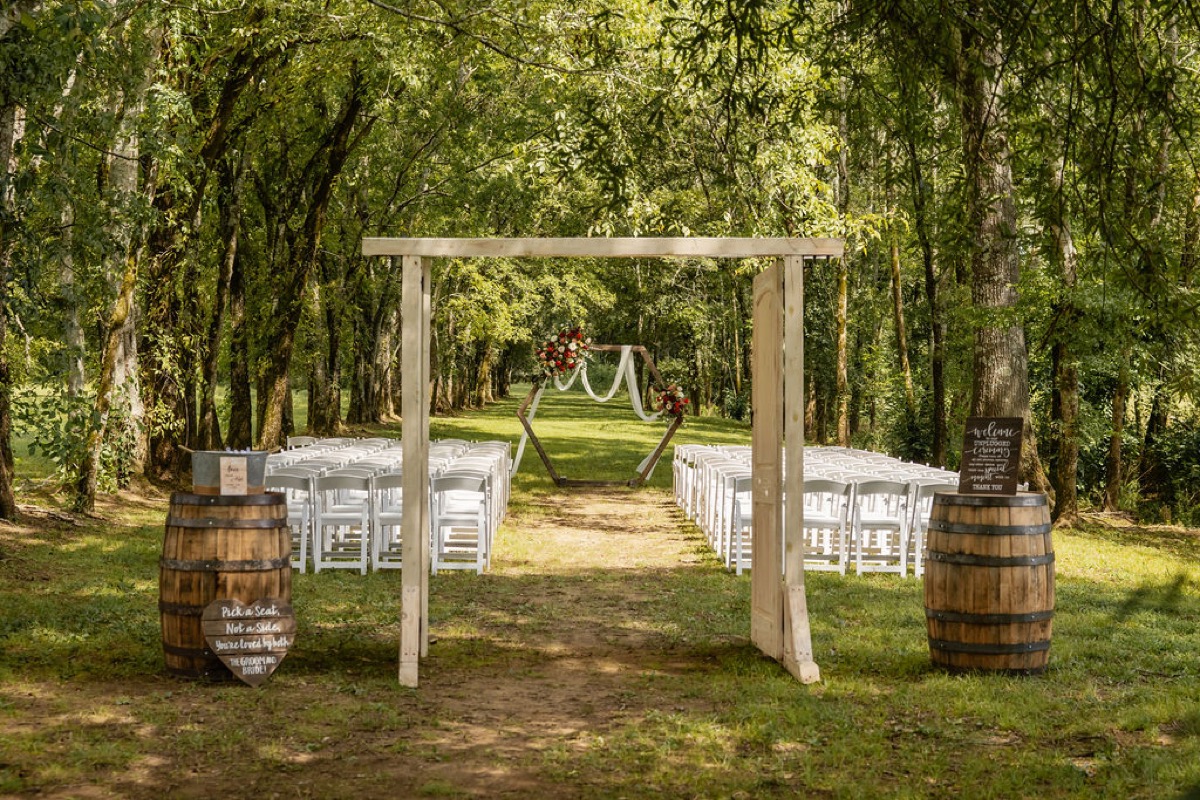 Erica & Randall Tunnel of Love aisle at Covey Creek with hexagonal arbor, white chairs, and whiskey barrels
