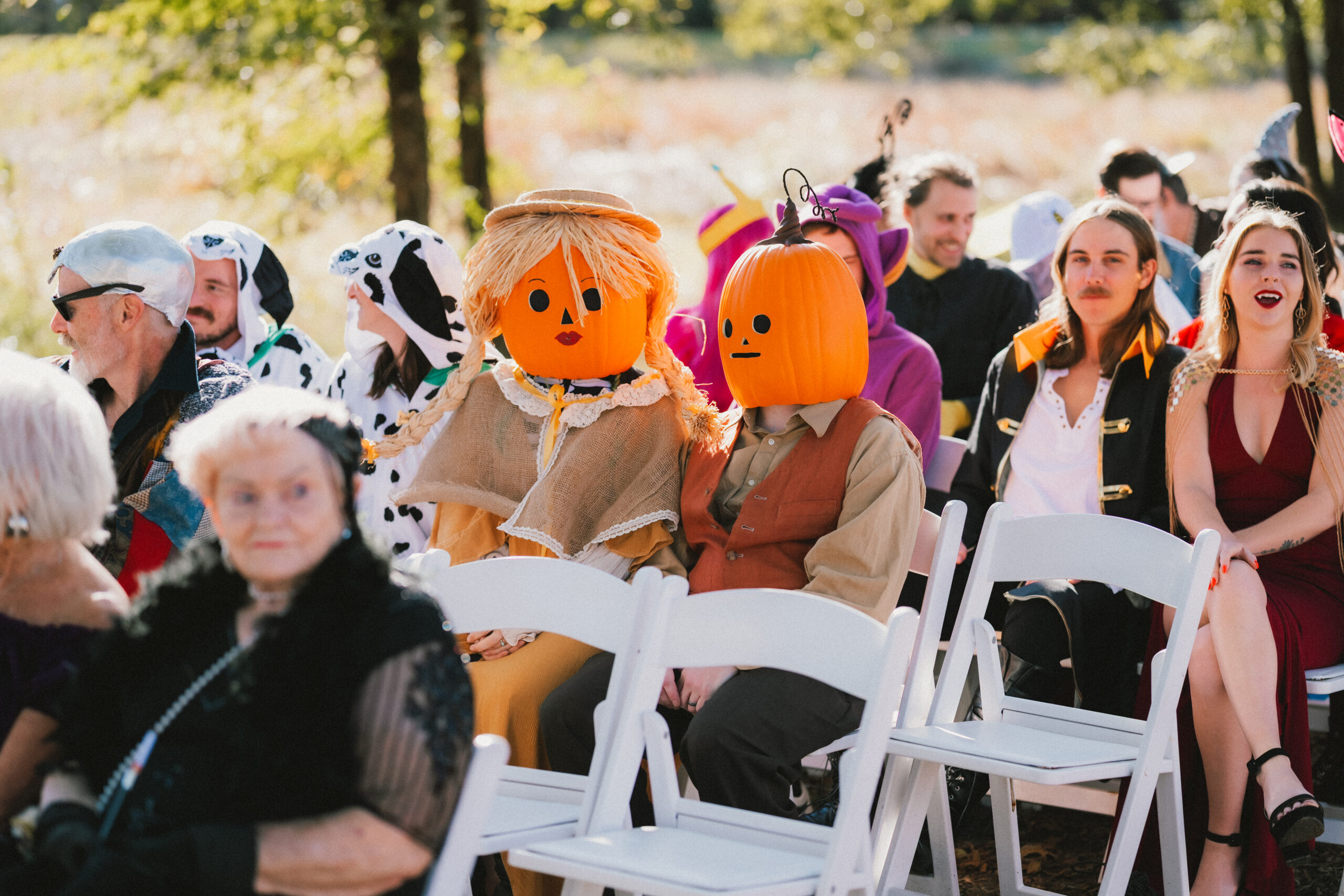 Guests in pumpkin masks and a purple Teletubby sit for Erin & Baxter's ceremony at Covey Creek