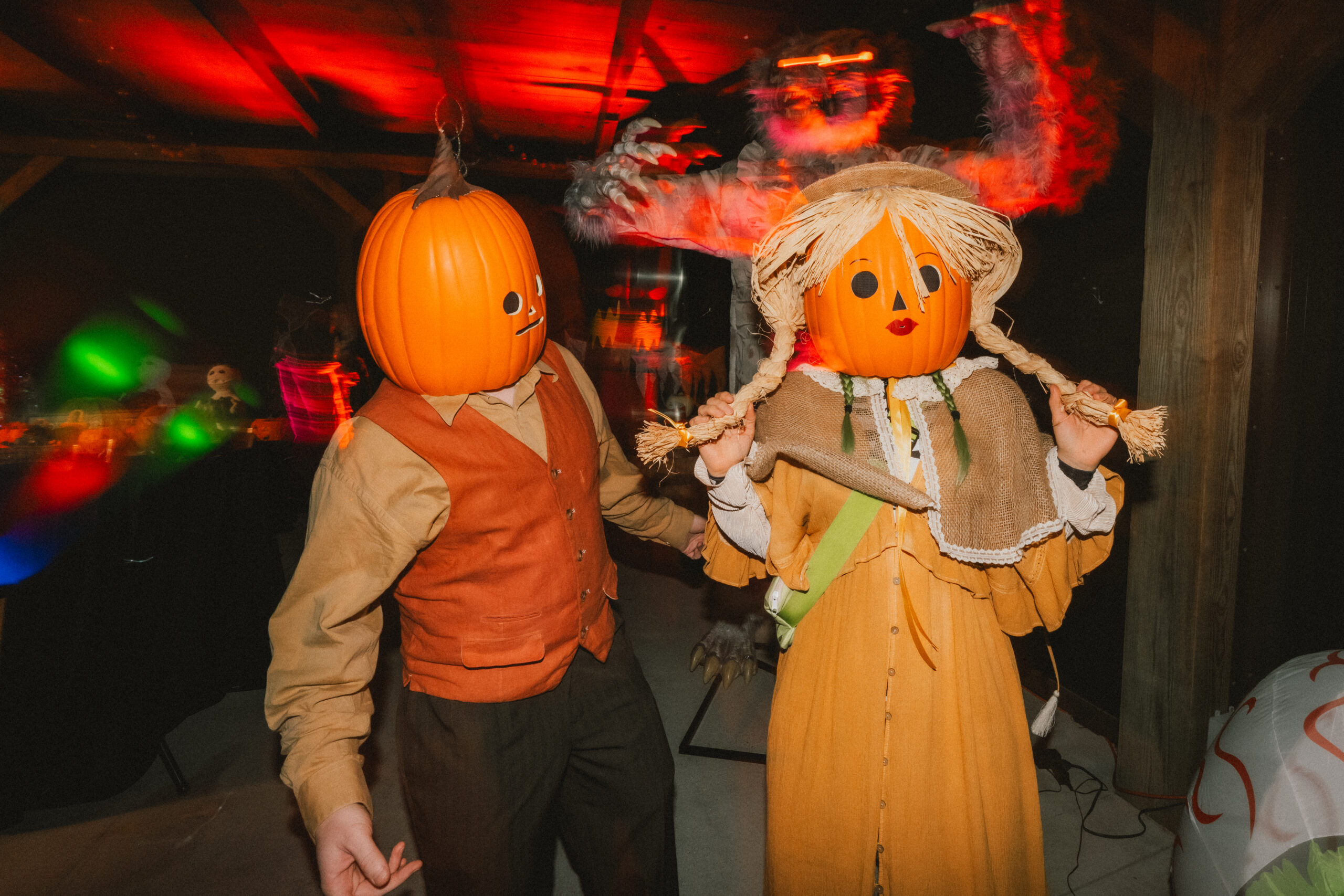 Erin & Baxter wear pumpkin-head masks on the barn dance floor with a furry monster at Covey Creek