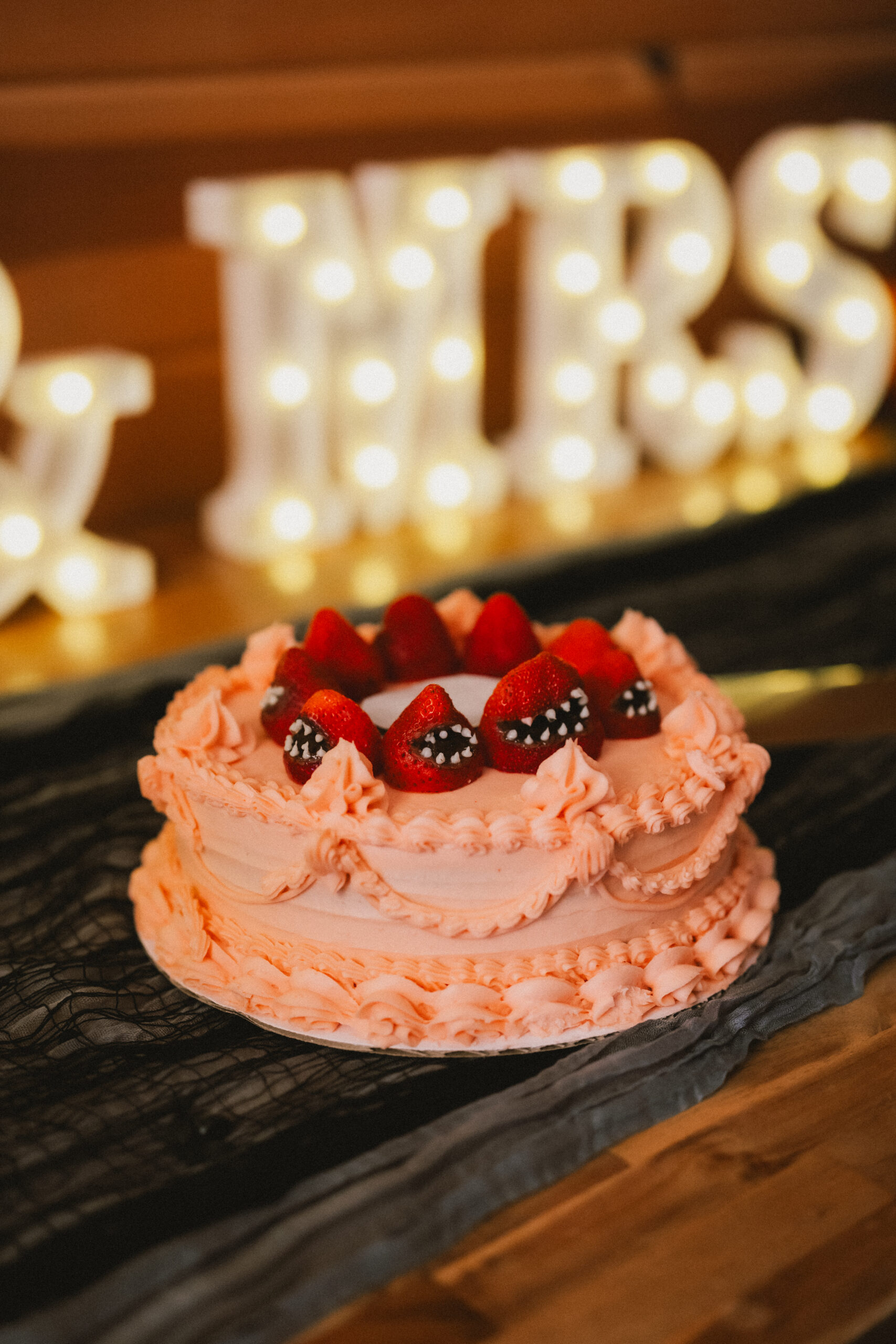 Peach wedding cake with monster strawberries beside lit MR & MRS for Erin & Baxter at Covey Creek