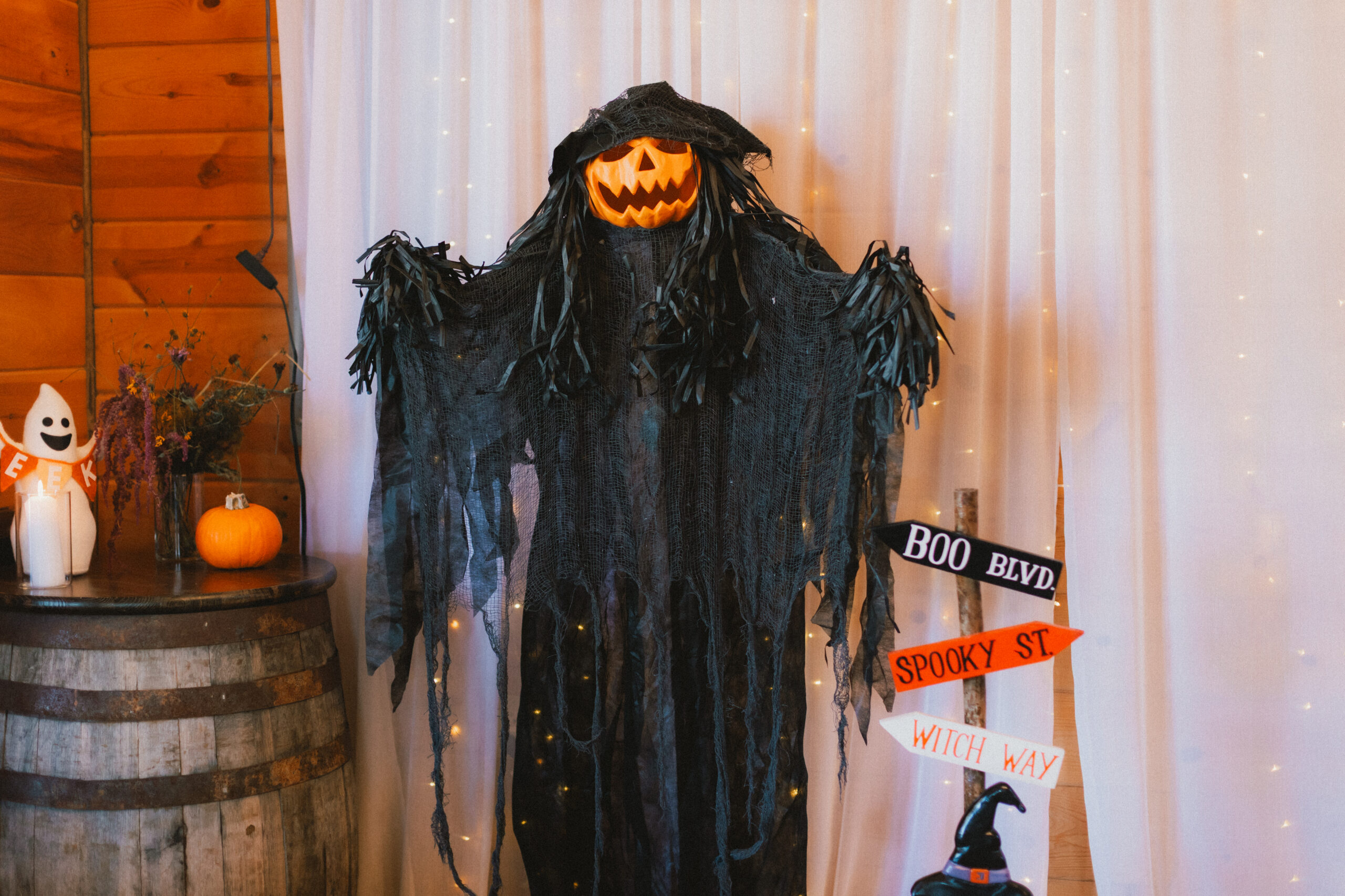 Jack-o'-lantern scarecrow stands by Boo Blvd signs and barrel pumpkins at Erin & Baxter's Covey Creek