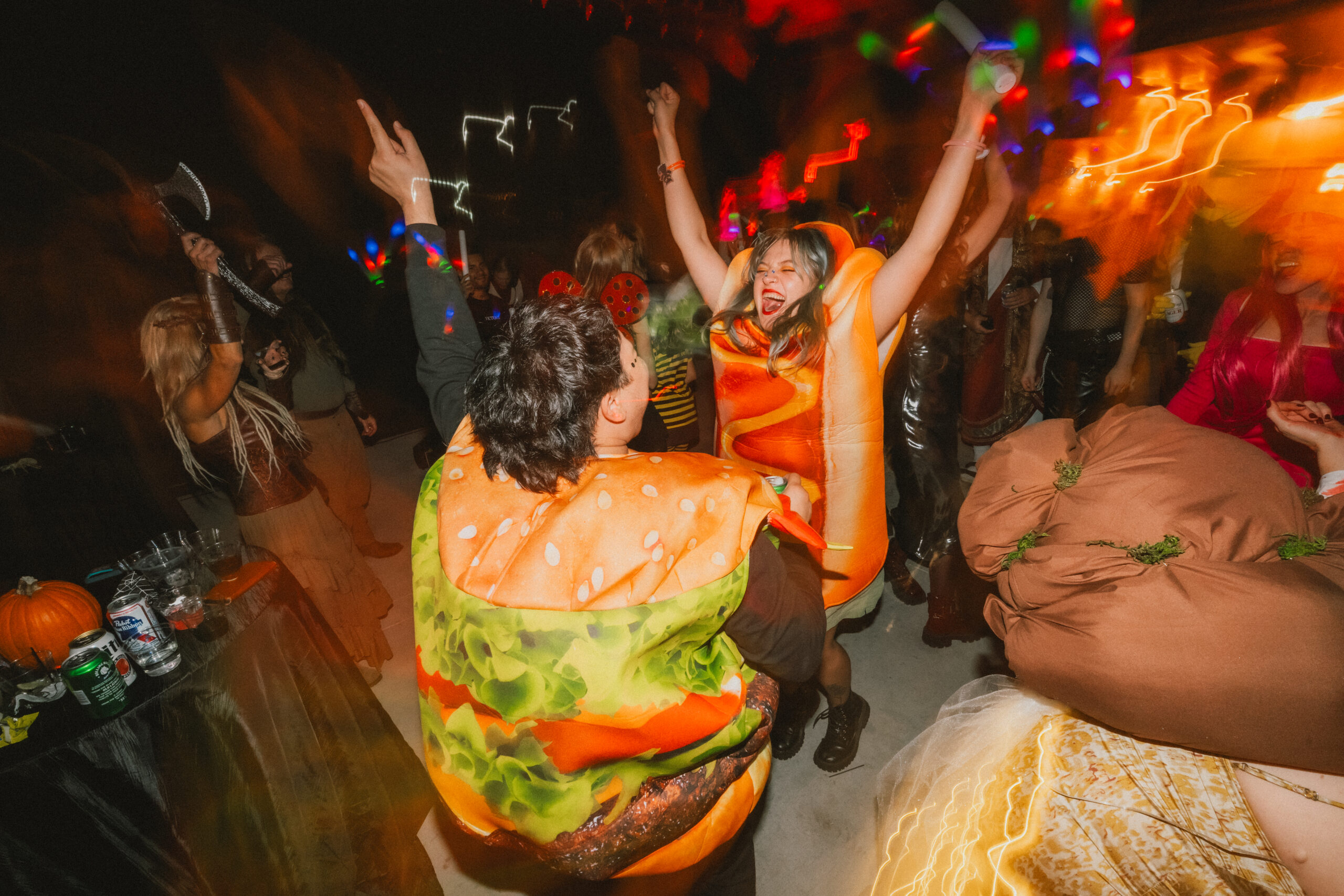 Guests in hot dog and cheeseburger costumes dance under neon trails at Erin & Baxter's Covey Creek