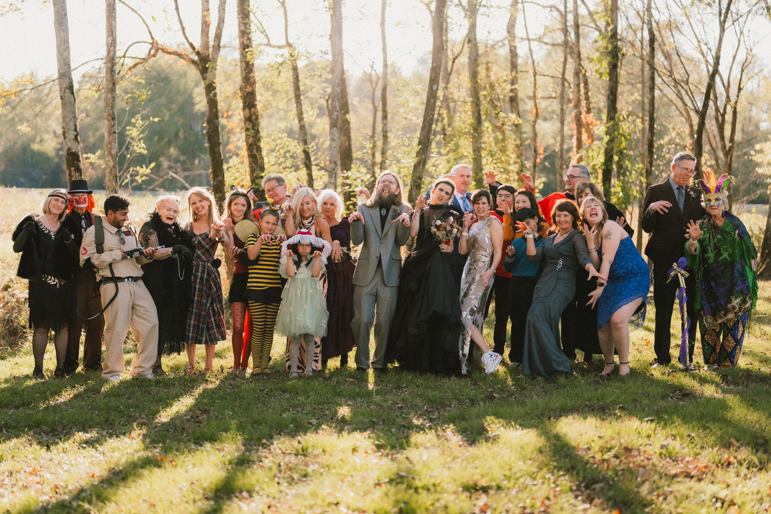 Erin & Baxter and costumed guests strike playful claw-hand poses in a wooded field at Covey Creek