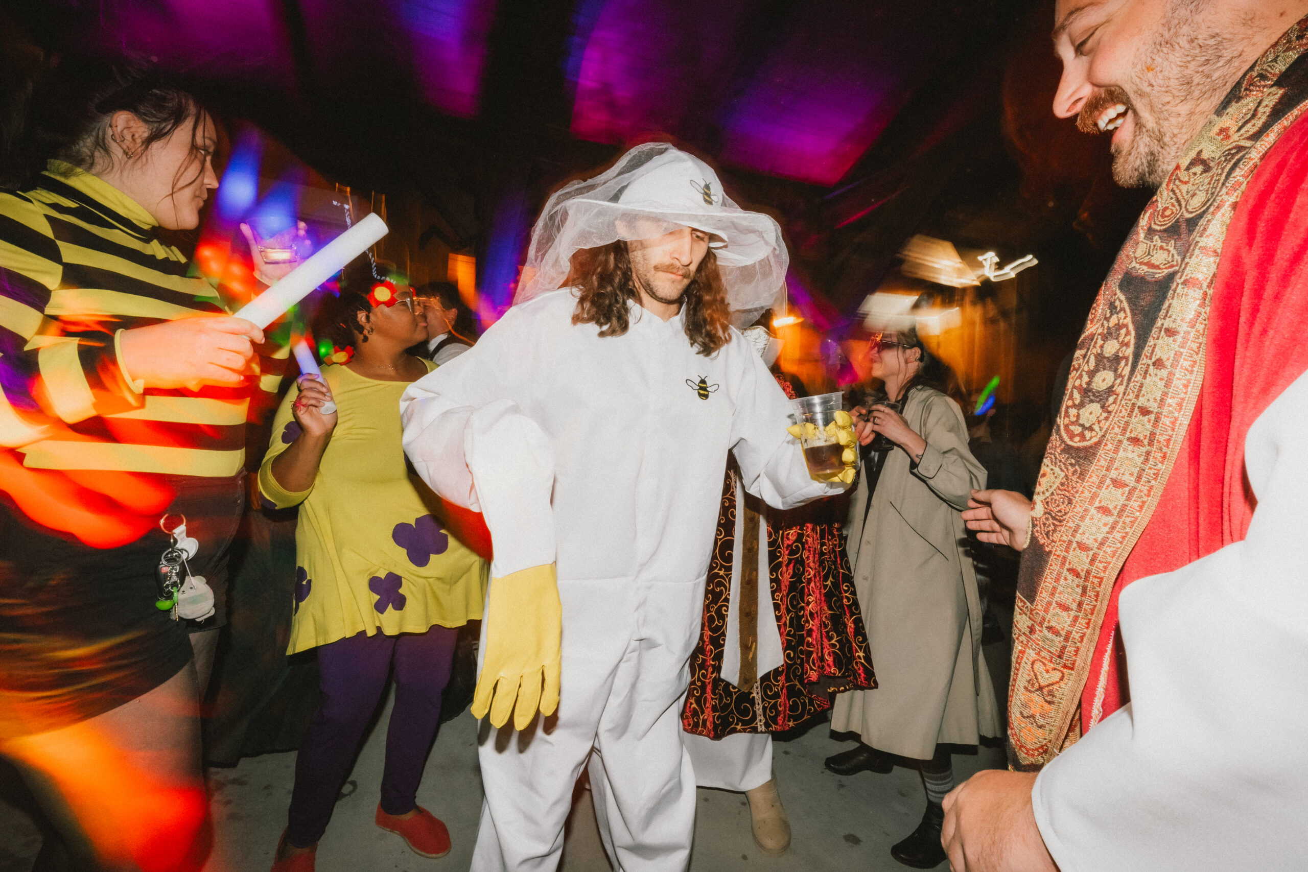 A guest in a white beekeeper suit dances amid colorful light trails at Erin & Baxter's Covey Creek