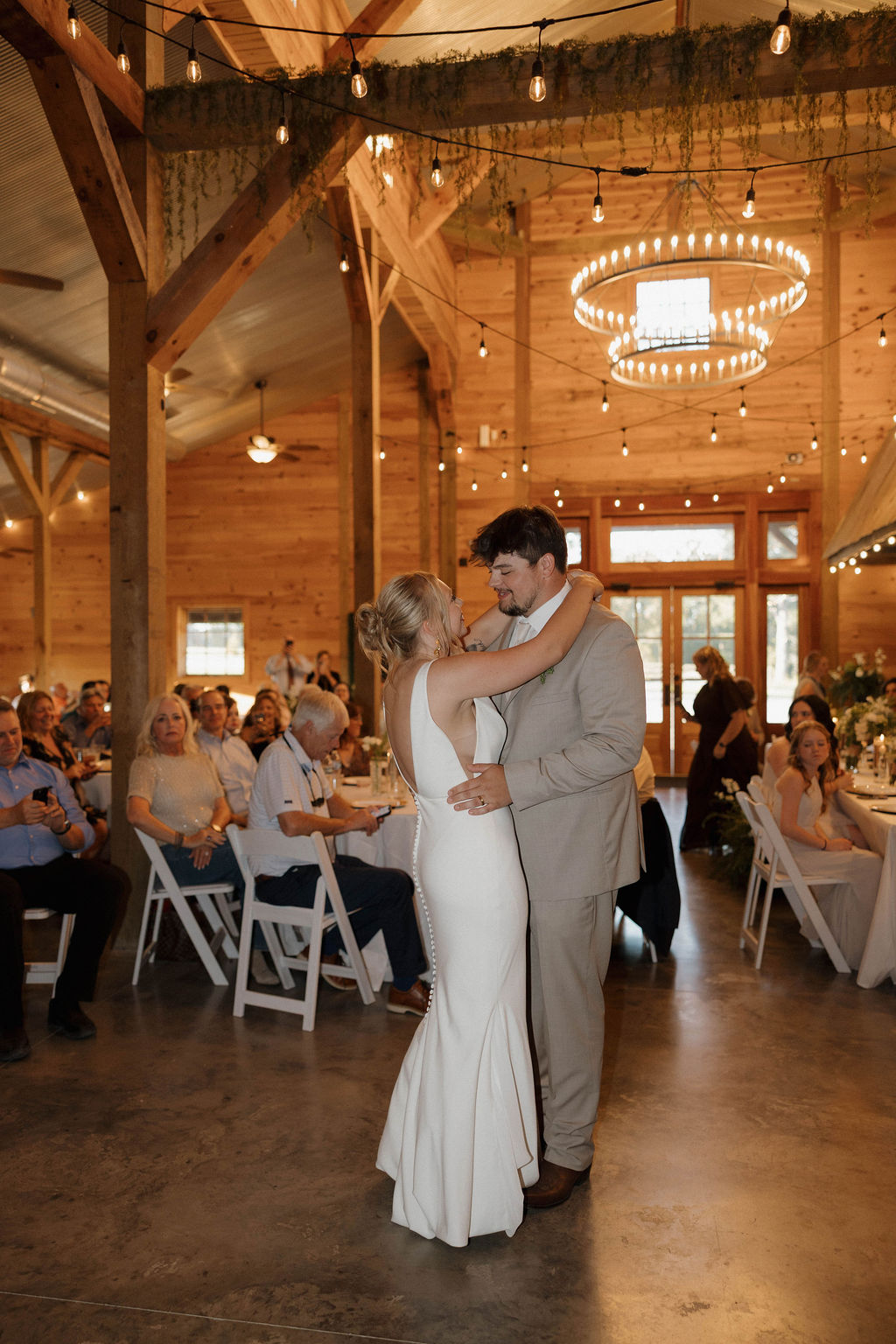 Hailey & Joseph share their first dance under string lights and a chandelier in the Covey Creek barn