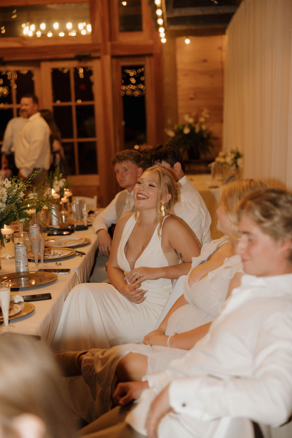 Hailey laughs at the gold-charged head table during Hailey & Joseph's reception at Covey Creek