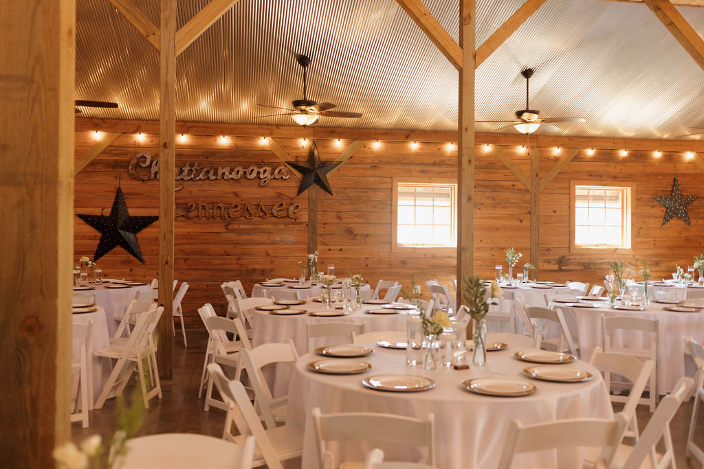 Hailey & Joseph reception tables with white linens, star décor, and Edison lights inside the Covey Creek barn