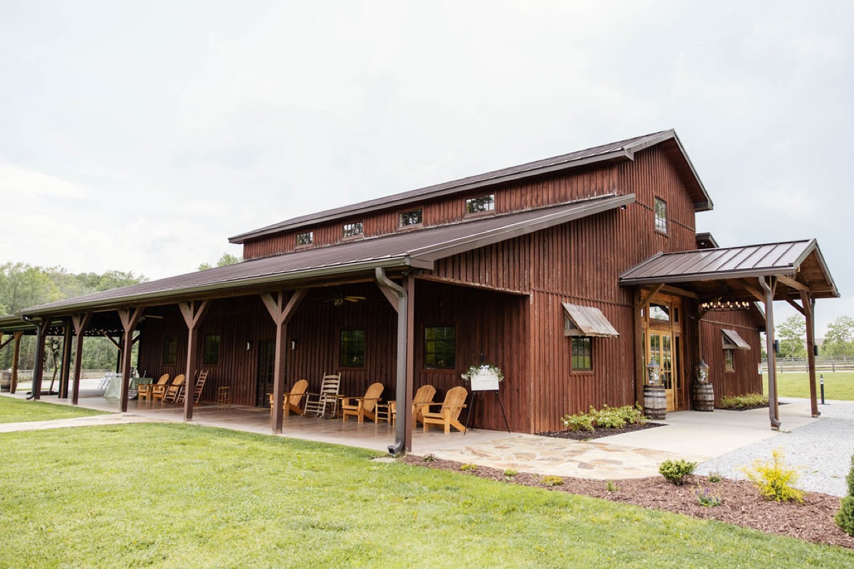 Covey Creek barn porch with rocking chairs and barrel-flanked doors set for Hannah & Nicholas's wedding day.