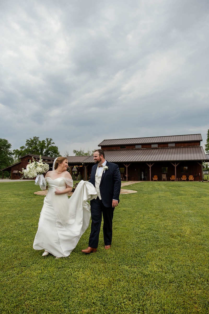 Nicholas carries Hannah's train as they cross Covey Creek's lawn before the barn porch, Hannah & Nicholas.