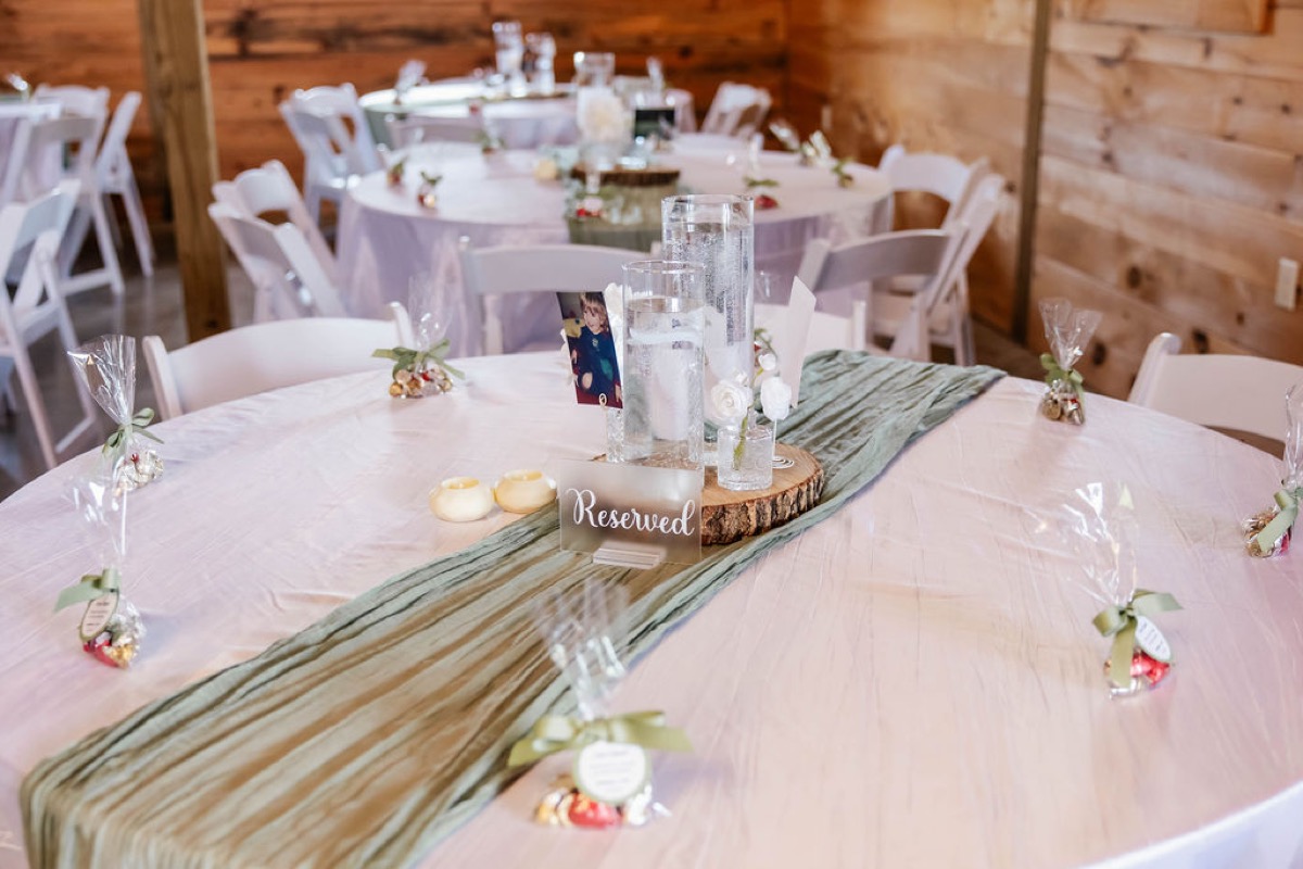 Sage runner, wood-slice centerpiece, and Hershey's favor bags on a guest table at Covey Creek for Hannah & Nicholas.