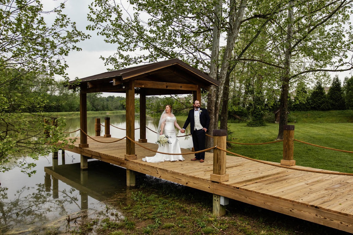 Hannah & Nicholas stand hand-in-hand on Covey Creek's pond dock under the covered pier pavilion.