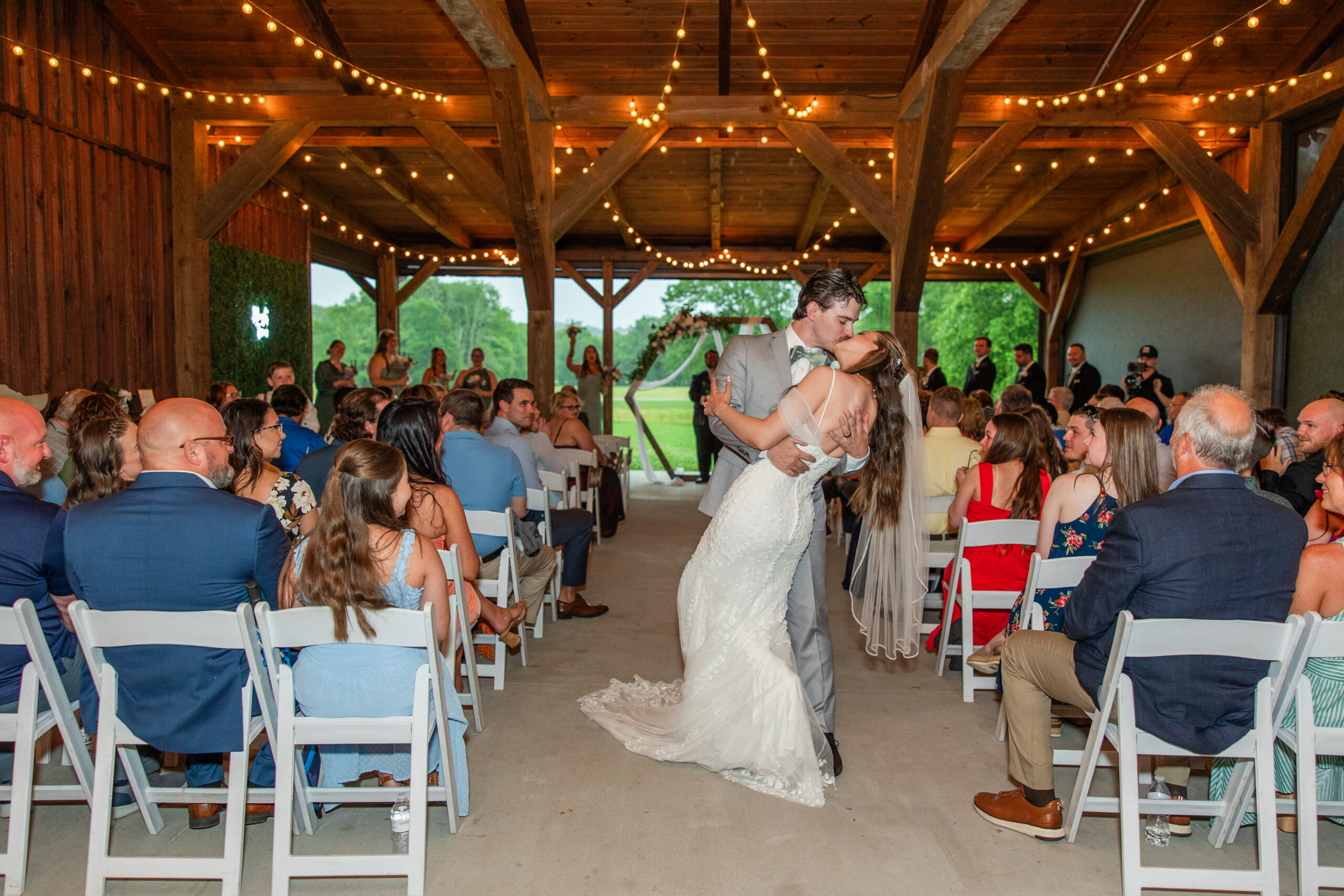 Ryan dips Hannah for a kiss down the aisle of the string-lit patio pavilion at Covey Creek.