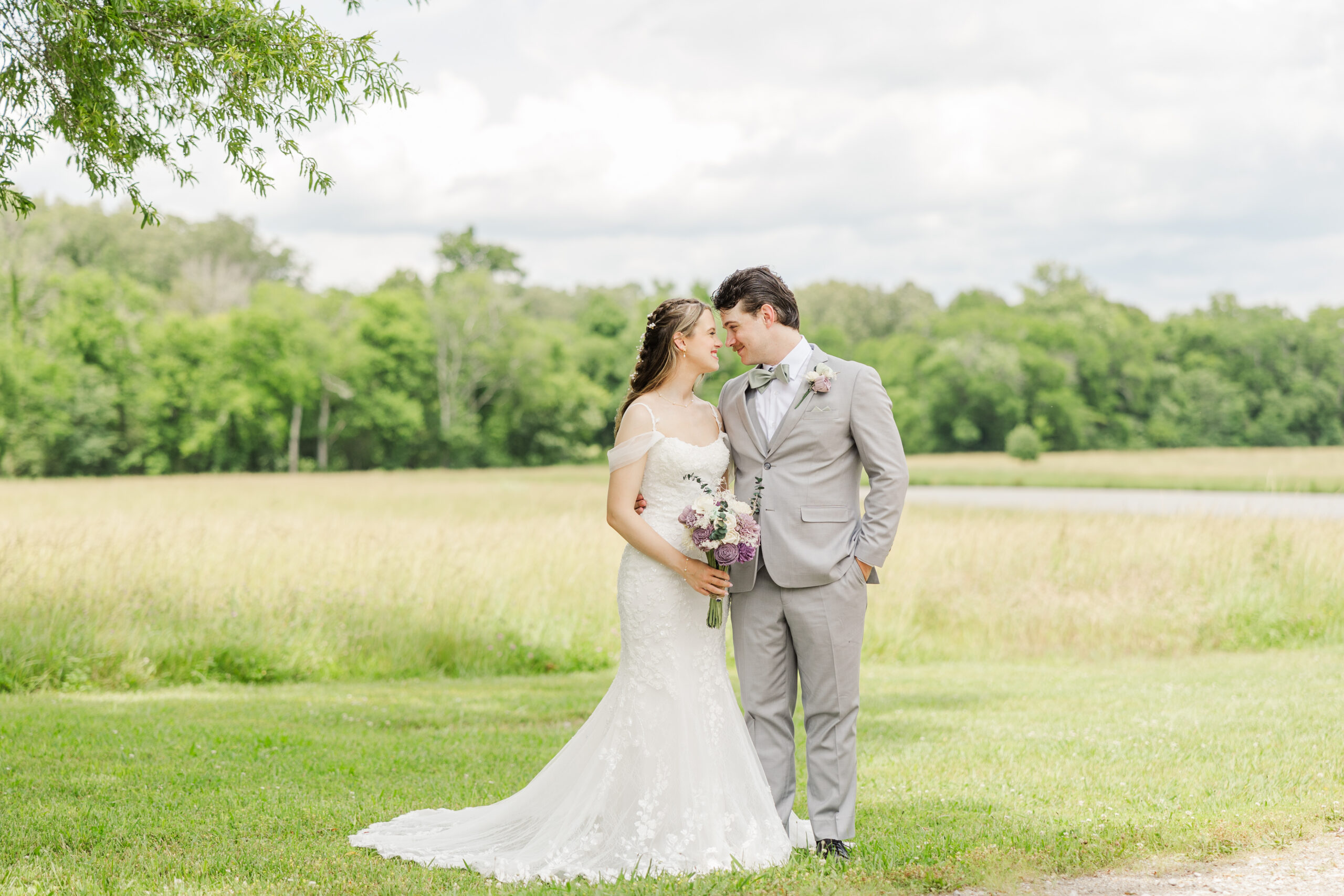 Hannah & Ryan stand forehead to forehead in a grassy meadow edged by trees at Covey Creek.
