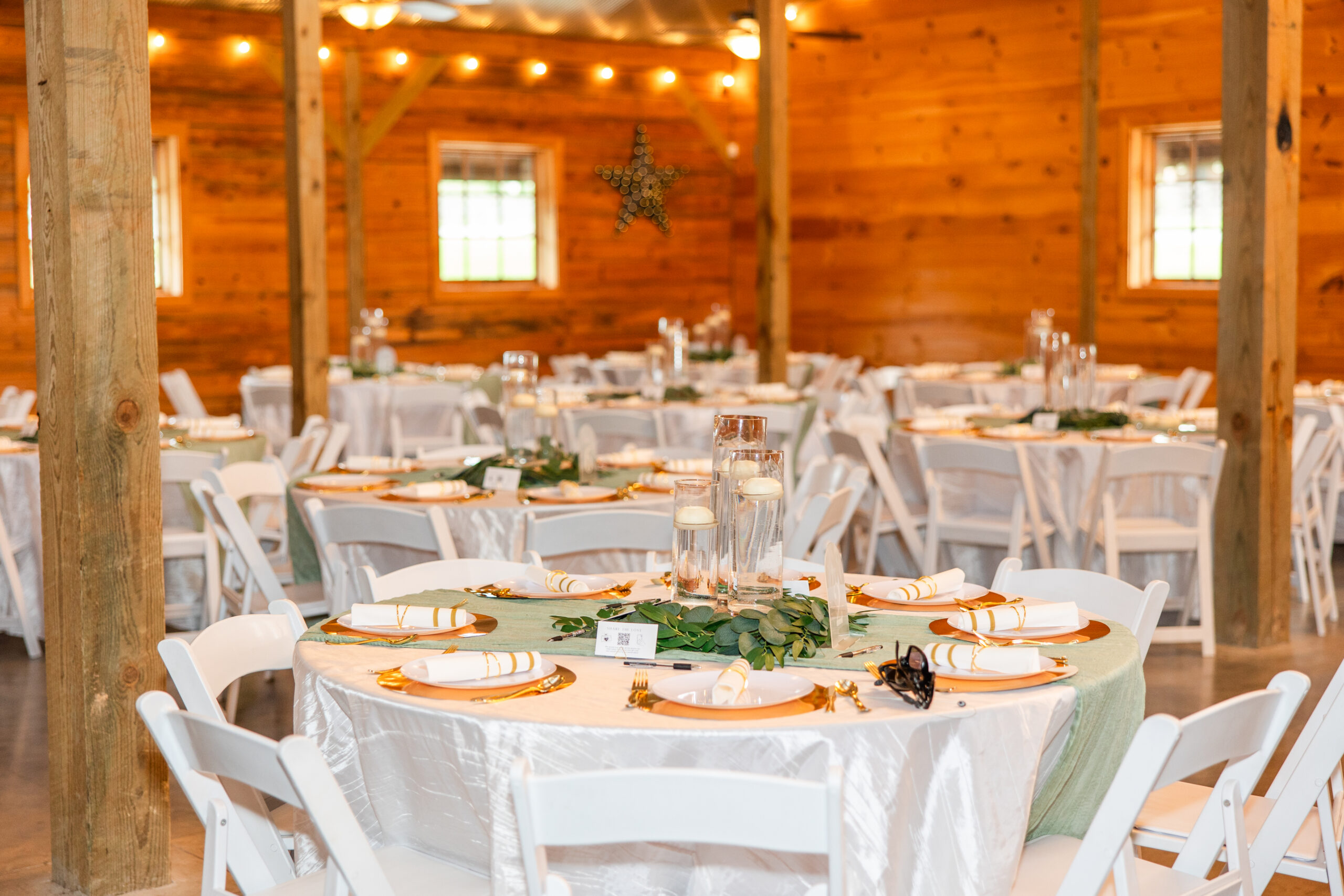 Sage runners and eucalyptus centerpieces dress reception tables in the barn at Covey Creek for Hannah & Ryan.