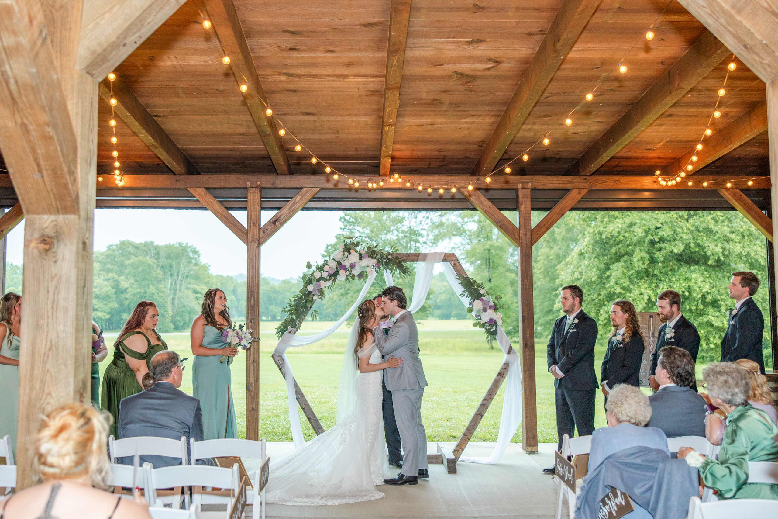 Hannah & Ryan share a kiss under string lights at the patio pavilion altar at Covey Creek.