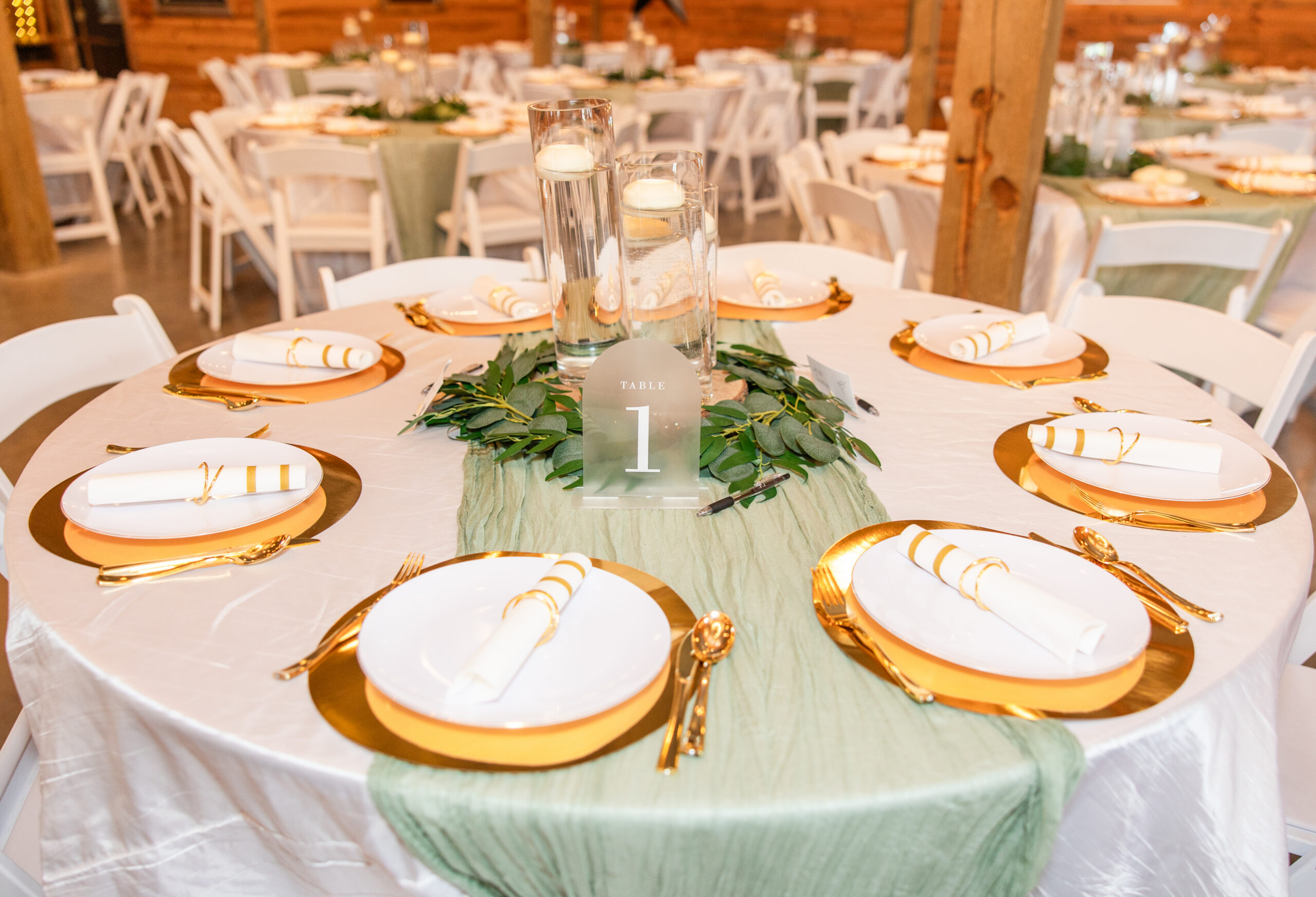 Table 1 at Hannah & Ryan's Covey Creek reception with eucalyptus, candles, and gold chargers.
