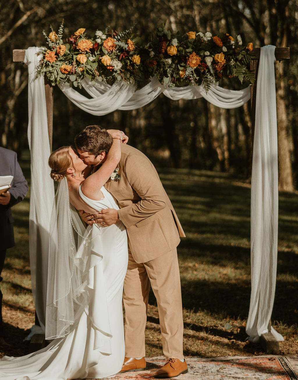 JJ & Will share a dipped first kiss under the floral Tunnel of Love arbor outdoors at Covey Creek