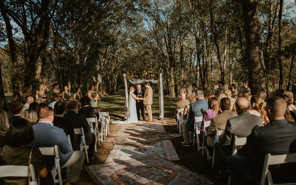 JJ & Will exchange vows under a floral arbor in the Tunnel of Love canopy with guests at Covey Creek