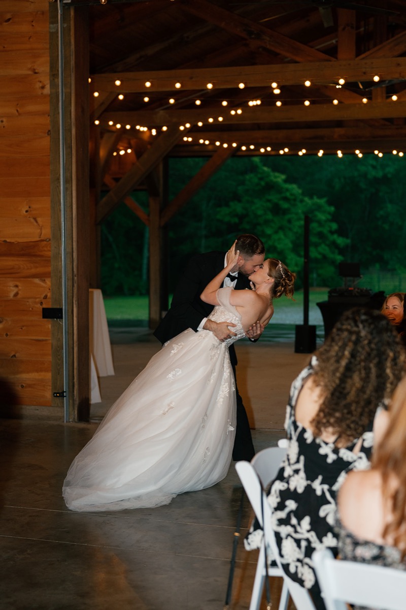 Katelyn & Josh share a dip kiss under string lights in Covey Creek’s open-air pavilion reception
