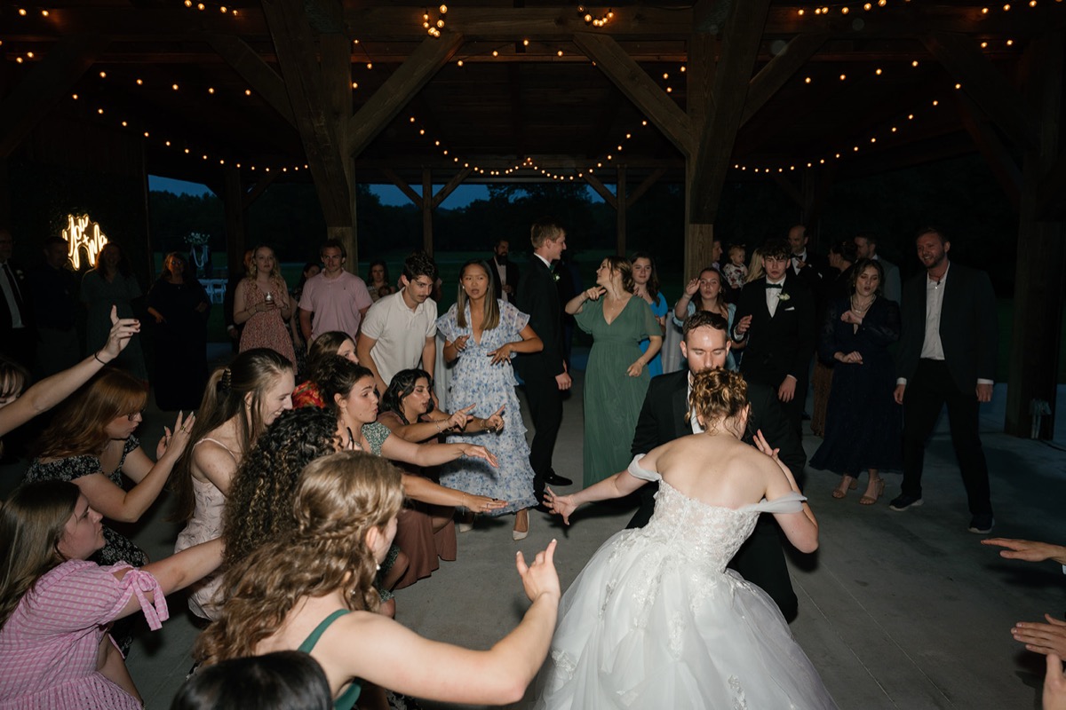 Katelyn & Josh dance as guests cheer under string-lit beams at Covey Creek’s pavilion reception